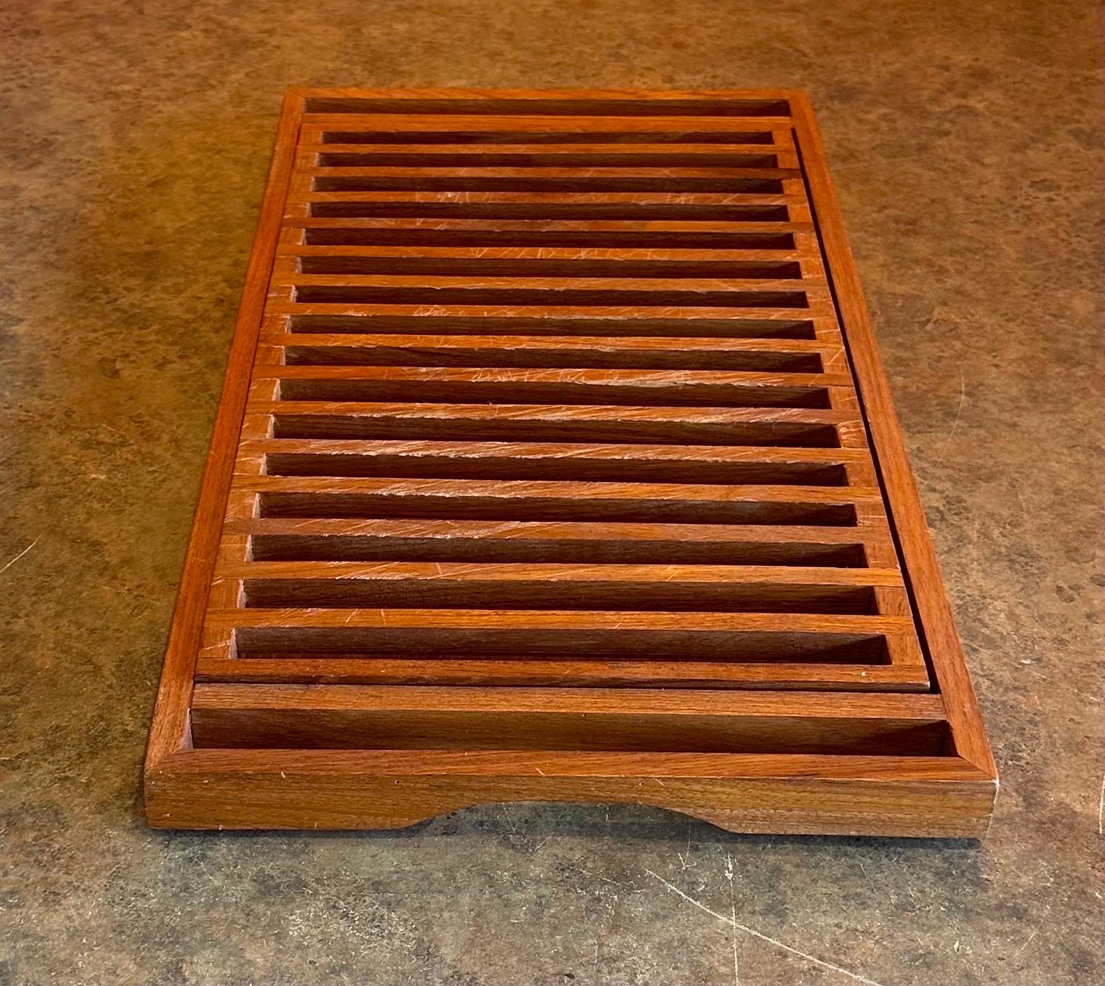 A very nice Danish modern teak bread cutting board with handles, circa 1970s. The board is in good vintage condition and measures 18