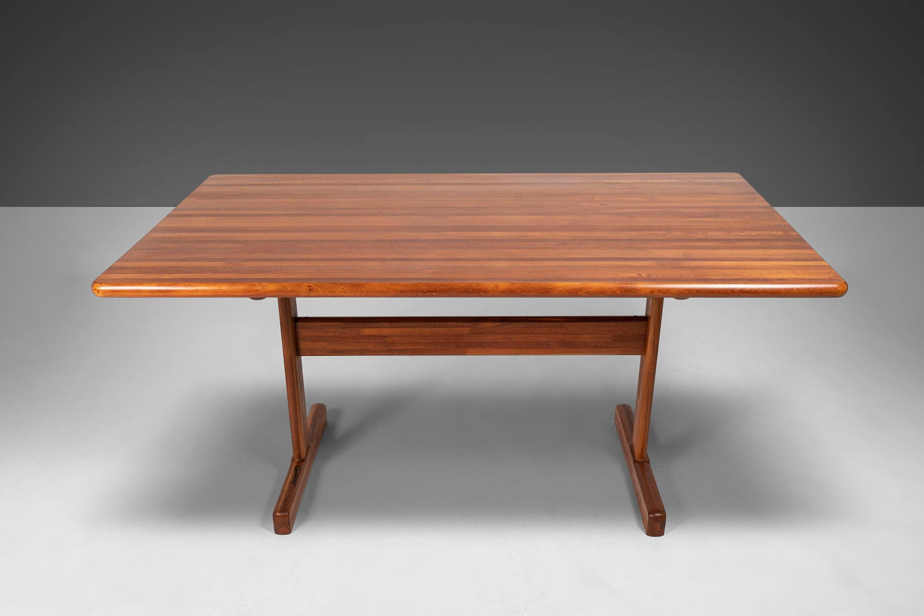 A newly refinished teak dining table which could also be used as an open workspace/desk. The teak butcherblock tabletop is stunning with varying shades of amber. Set on an angular t-base tied together by a crossbeam. Seats 4-6.