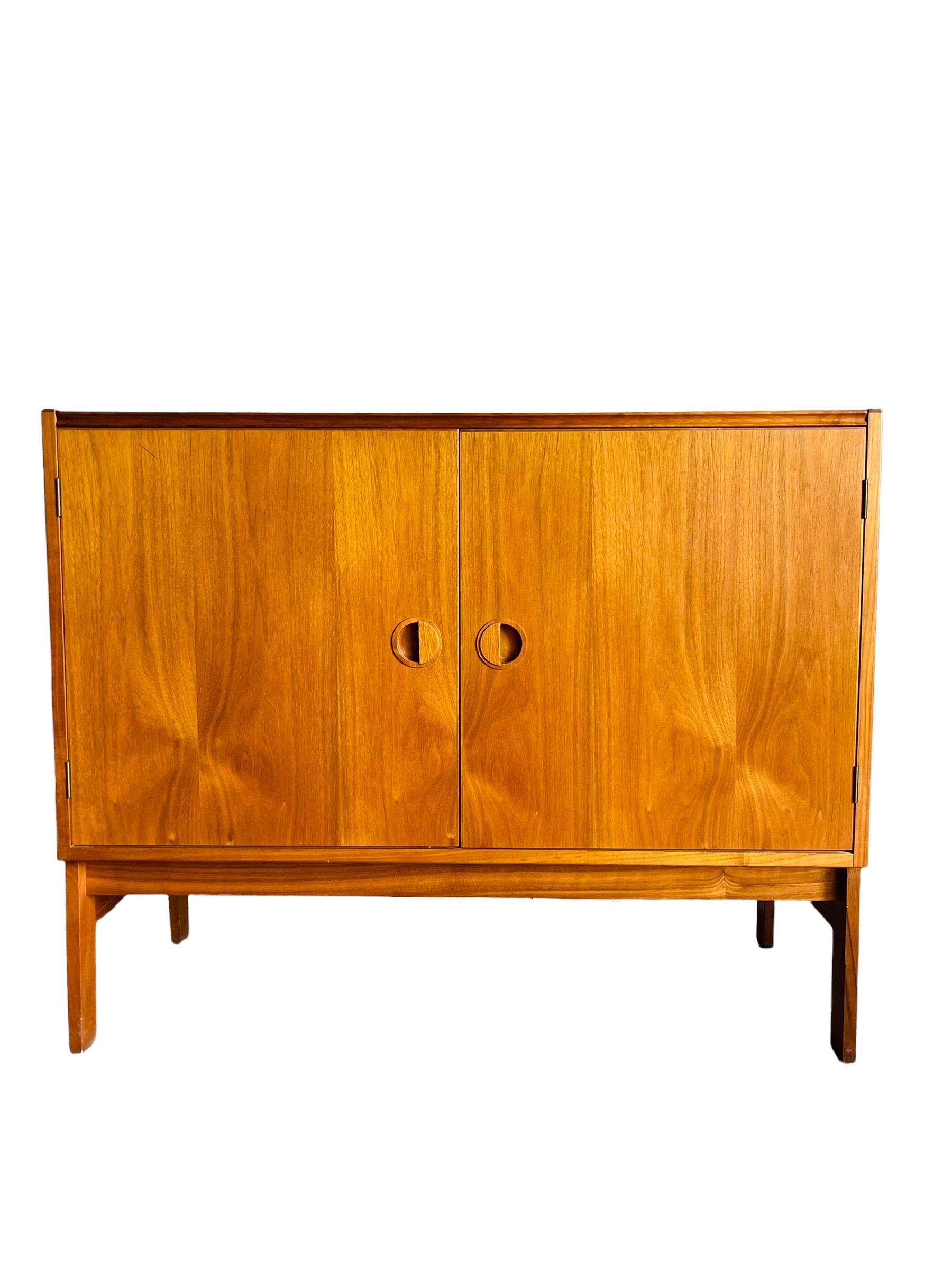Beautiful Danish modern teak record cabinet by Hansen Guldborg of Denmark. This cabinet is equipped with two doors to open to multiple adjustable shelves and a lift up door on top for easy access to a record player. This versatile cabinet can be