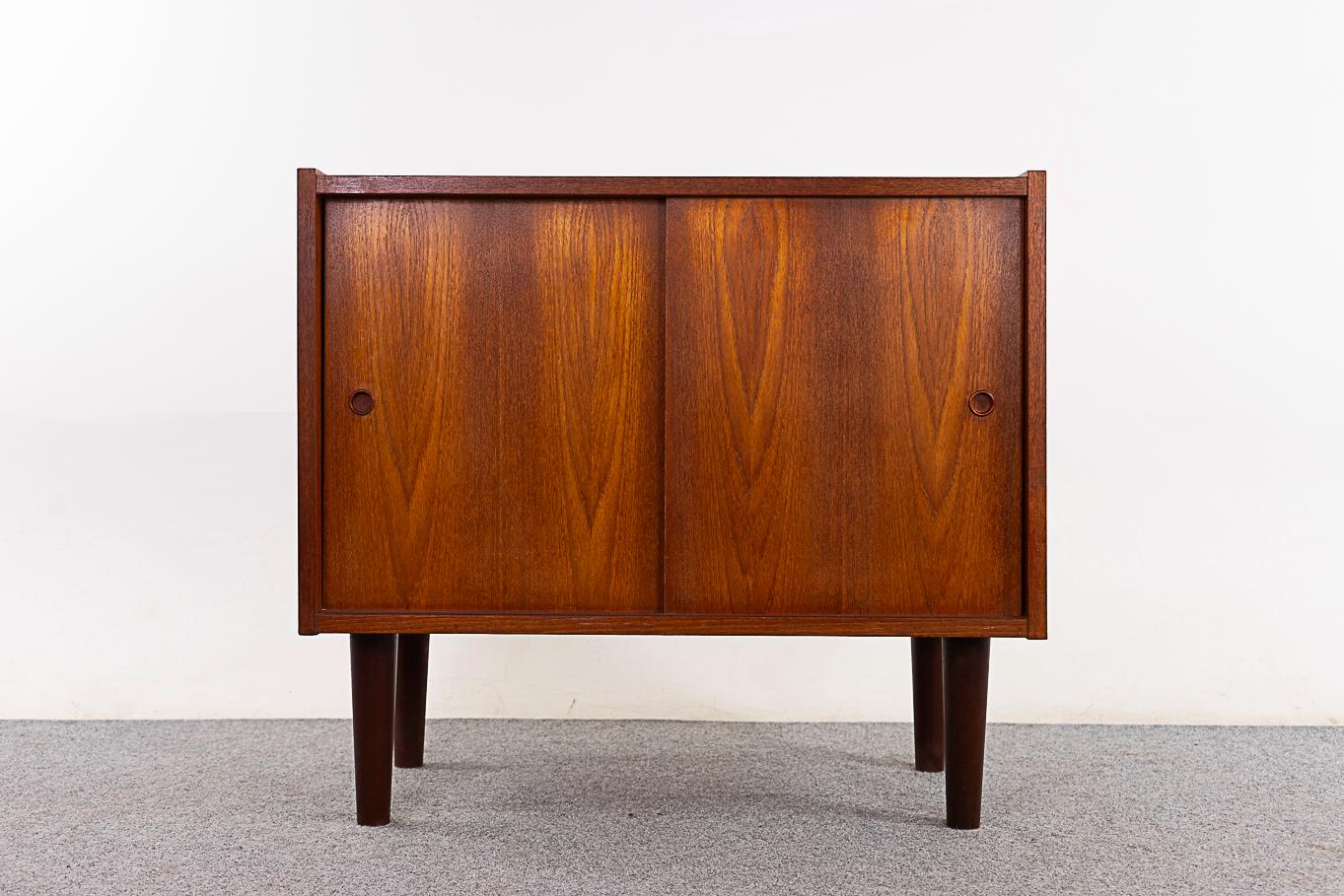 Teak Danish cabinet, circa 1960's. Clean, simple lines, lovely book-matched veneer case and solid tapering legs. Height adjustable shelf and sleek finger pull handles.  

Unrestored item with option to purchase in restored condition for an