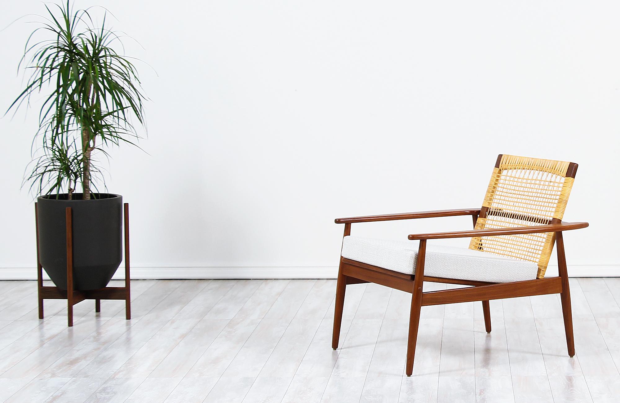 Danish modern lounge chair designed by Hans Olsen for Juul Kristensen in Denmark, circa 1960s. This iconic chair by Hans Olsen is constructed from solid Afromosia teak wood that is found only in Africa, a newly Danish woven caned backrest and new