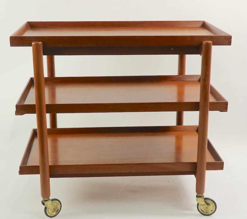 Hard to find three shelf version of the classic the Danish Modern serving cart designed by Poul Hundevard. The cart has a sliding top tray, and two removable shelves under the top surface. This example is in very good, clean and original condition.
