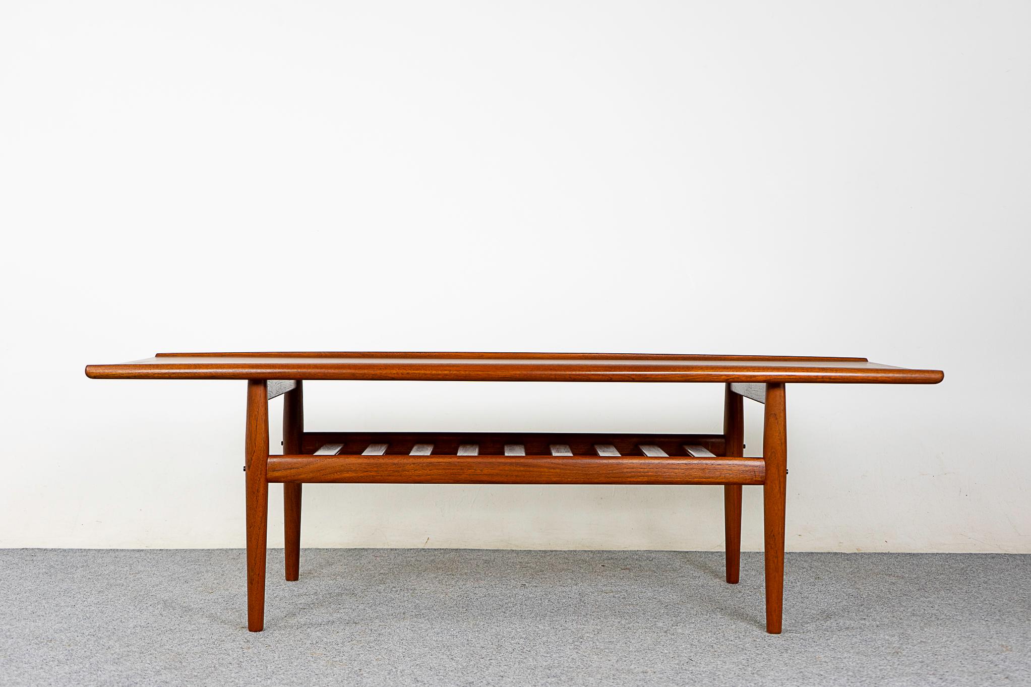 Teak Danish coffee table by Svend Aage Eriksen for Glostrup, circa 1960's. Top shows beautiful book matched veneer and solid wood curved edge along its length. Slatted shelf gives an airy impression, perfect for magazines & remote controls. Danish