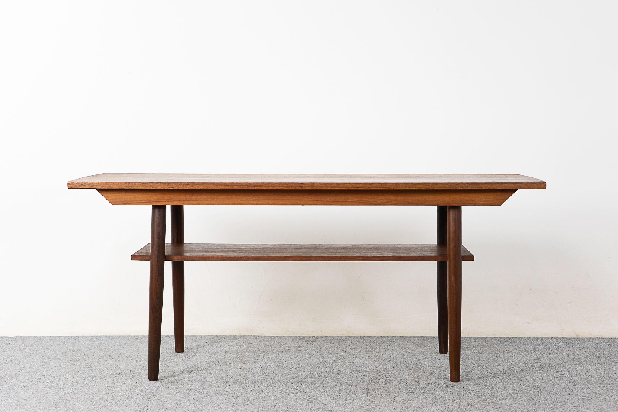 Teak mid-century coffee table, circa 1960's. Top surface has beautiful book matched veneer, elegant  contrasting legs. Convenient lower shelf, hide away clutter!