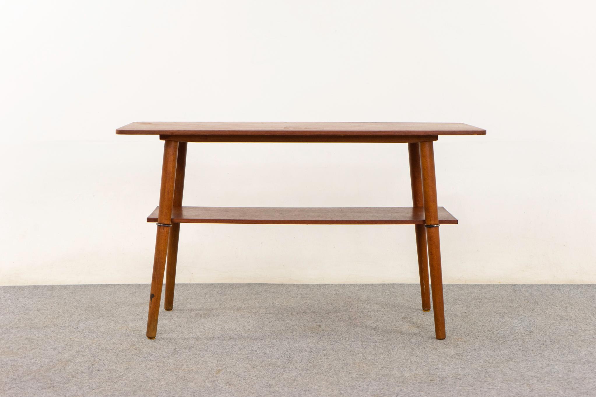 Table basse danoise en teck, circa 1960. Magnifique plateau en placage assorti aux livres, pieds massifs évasés et étagère pratique avec accents métalliques !

Pièce non restaurée avec option d'achat en condition restaurée pour un supplément de 200