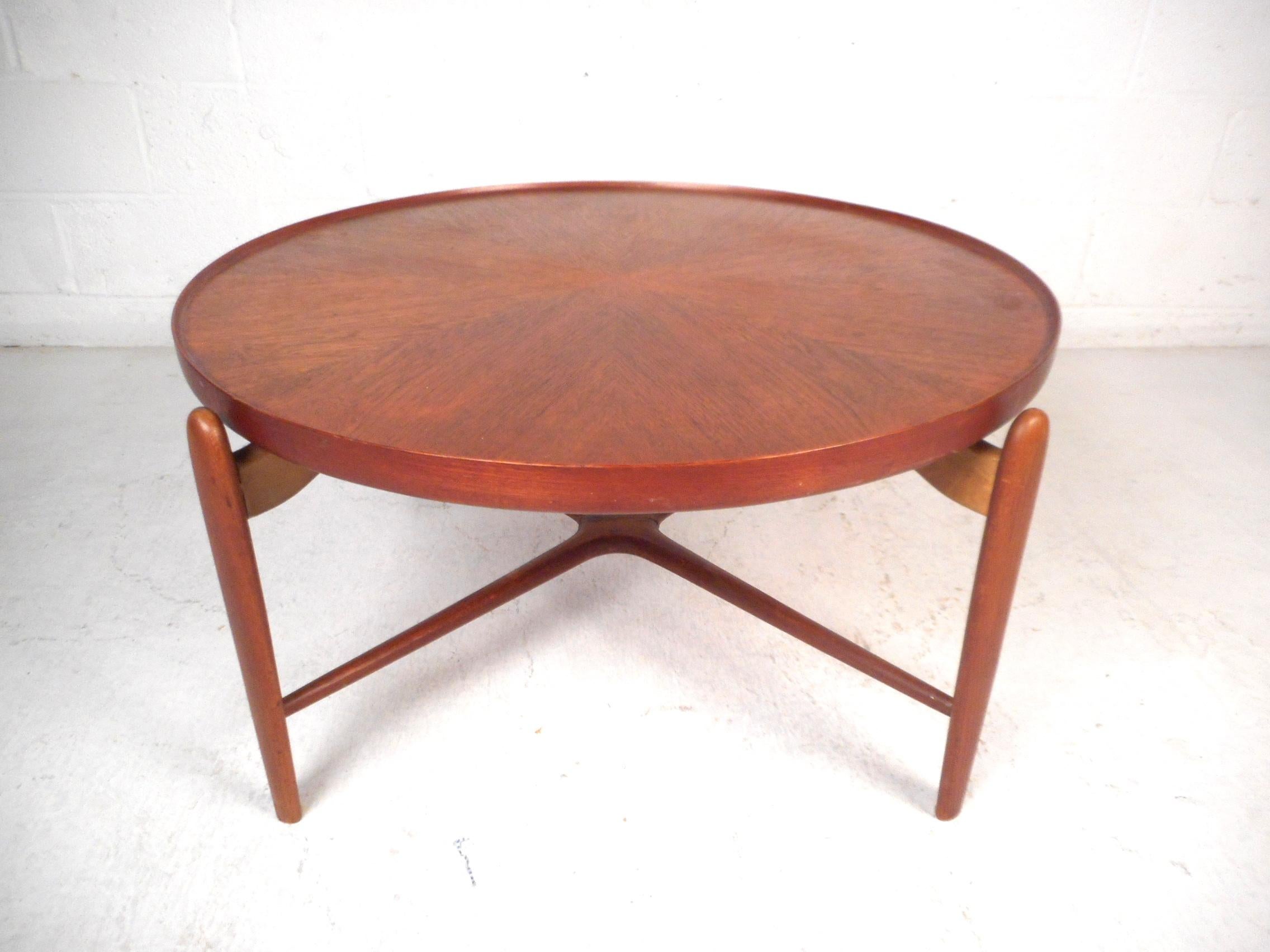 Stunning Danish modern coffee table. Sturdy teak wood construction. Stylish design with raised edges on the tabletop, tapered legs, and sculpted stretchers connecting the four legs of the table. Tabletop shows an interesting four-directional grain