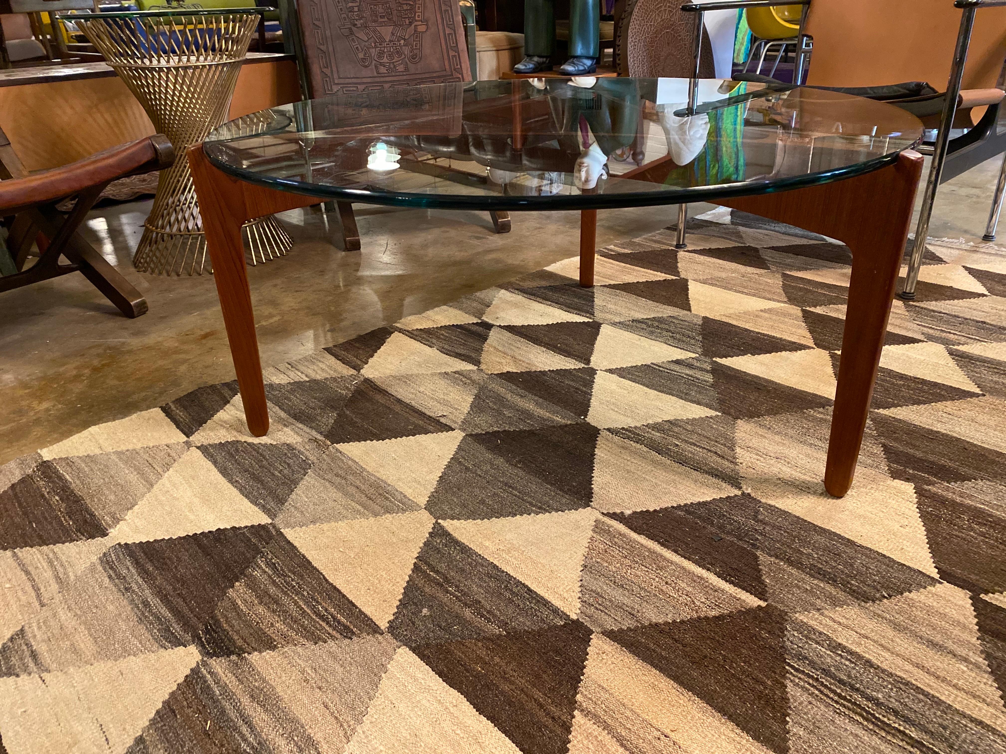 Mid-Century Modern teak coffee table designed by Sven Ellekaer for Christian Linneberg Mobelfabrik, Denmark, circa 1960s. This vintage coffee table features an elegant teak base with a thick glass top that is almost an inch thick. This Danish modern