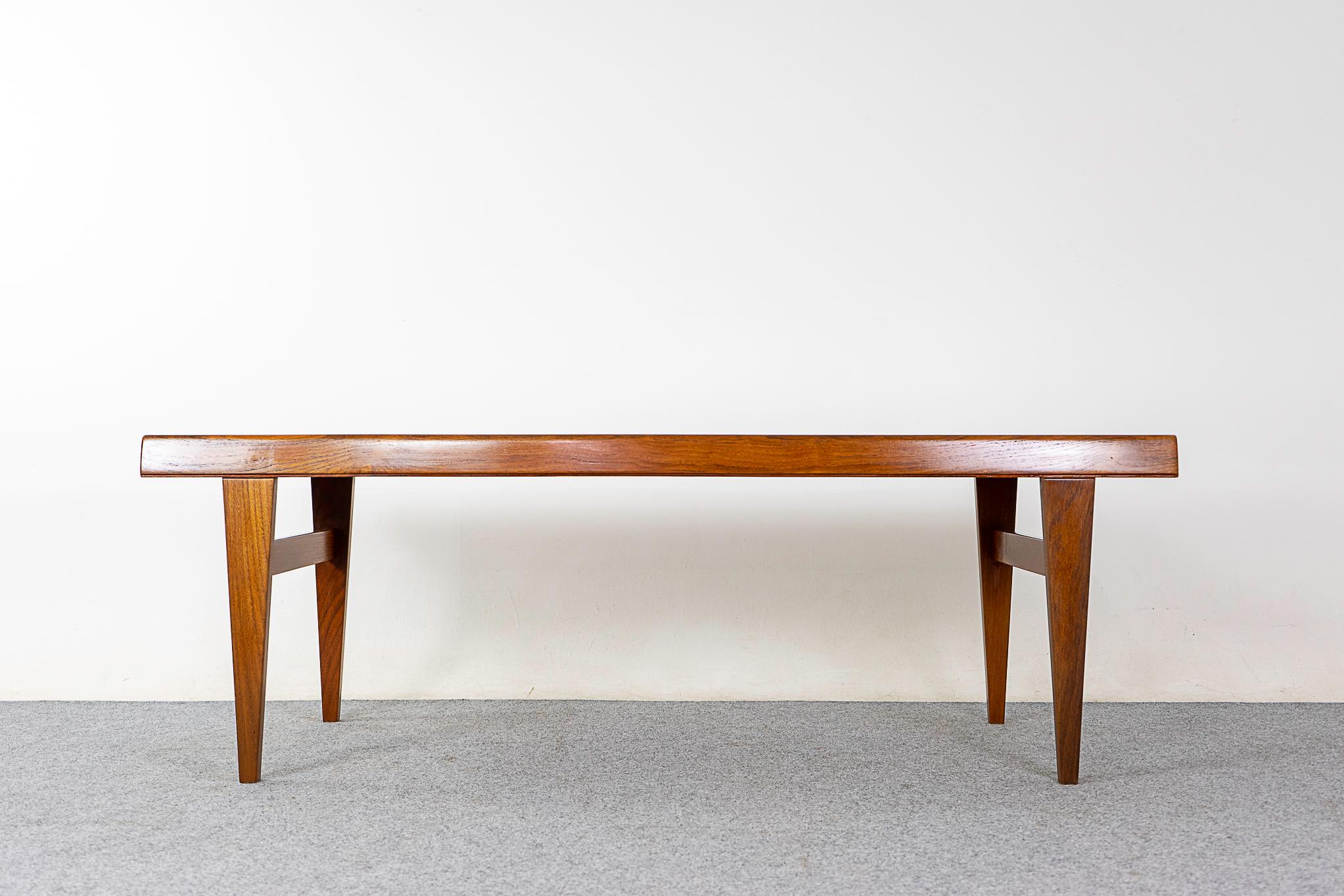 Teak mid-century coffee table, circa 1960's. Beautifully robust table with generous dimensions. Unique curved edge, slim drawer on one edge, pullout melamine surface on the other! Sleek flat facing angular legs with cross bars for longevity.     

E