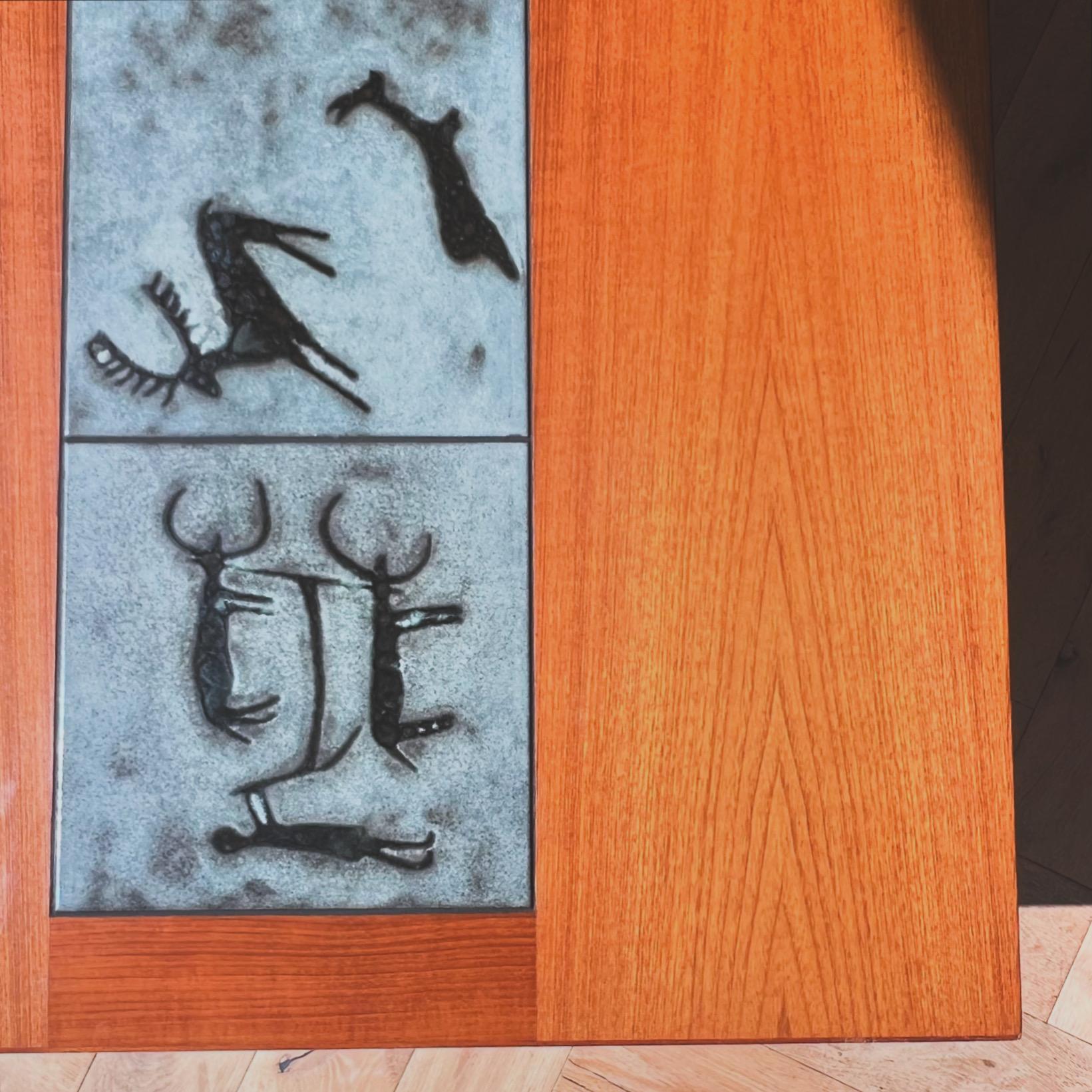 Moderner dänischer Couchtisch aus Teakholz mit eingelegter Fliese mit einem seltenen prähistorischen Motiv, das Gangsø Møbler zugeschrieben wird, ca. Mitte der 1960er Jahre. Mit stabilem Eisen-Doppelsockel. Töne von Kastanie, Zinn und Moos. Gut