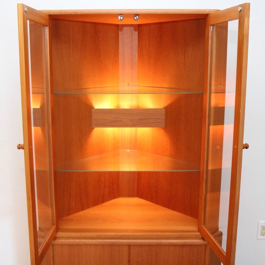 This Danish teak corner hutch is a nice 70s survivor. Lighted upper cabinet features two glass shelves. Lower section has one adjustable teak shelf. This a great solution for corners that used to just take up space.