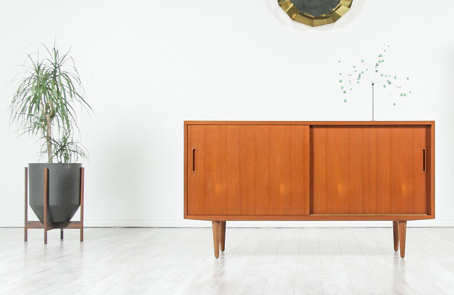 Elegant modern credenza designed by Carlo Jensen for Hundevad & Co. in Denmark, circa 1960s. This compact credenza features a sturdy teak wood construction sitting on four tapered legs with warm teak grain detail on the case and beechwood interior.