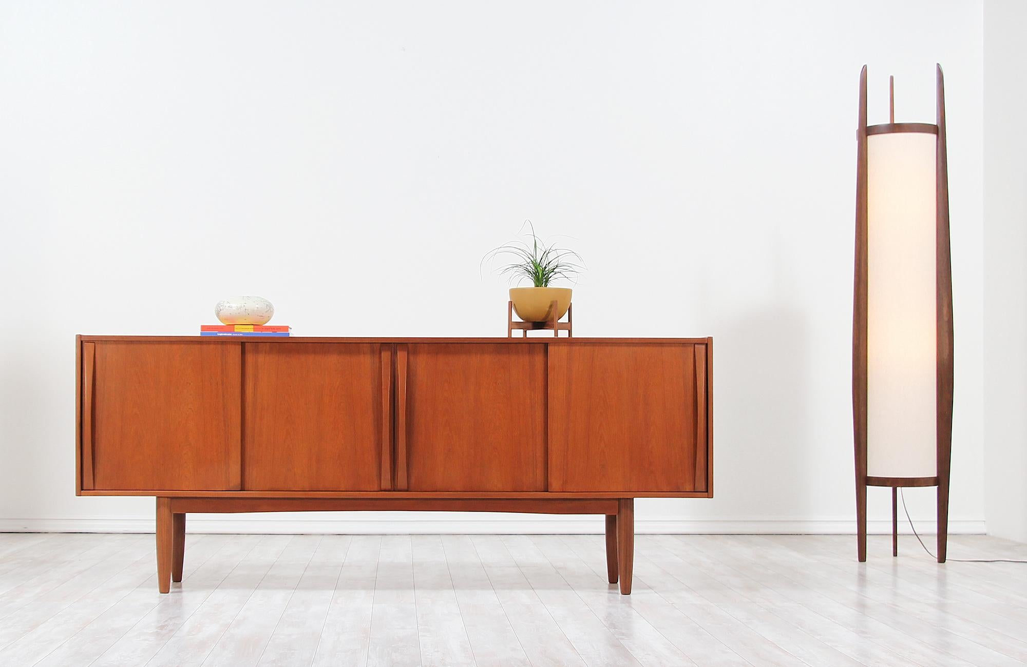 Danish modern credenza designed and manufactured by Dyrlund in Denmark, circa 1960s. This stunning teak wood design is fully refinished and shows a subtle grain pattern throughout. The four sliding doors have a sculpted handle that helps each door