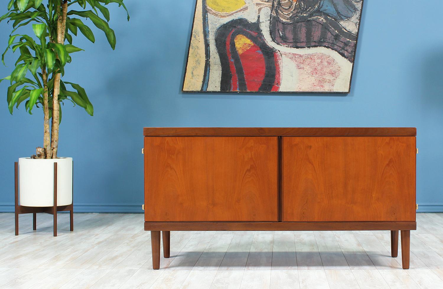 Compact credenza designed by Hans Olsen and manufactured by Hans Olsen Design in Denmark circa 1950’s. This practical credenza features a two-tone teak wood body, with mostly Burma teak and Afromosia teak trimming and tapered legs. This credenza