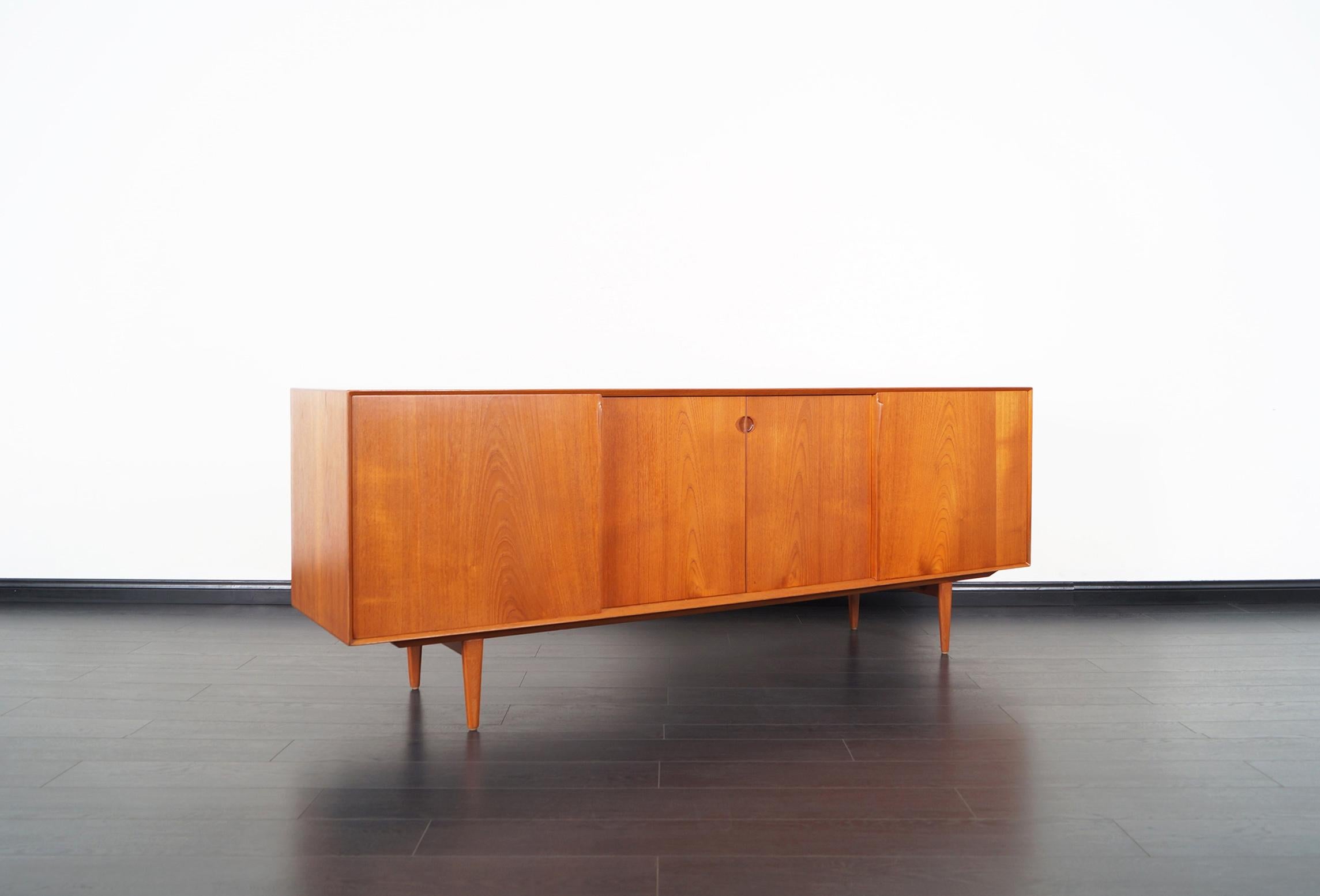 Stunning Danish modern teak credenza designed by Henry Rosengren Hansen for Brande Møbelindustri, Denmark, 1950s. Features four sliding doors with sculptural pulls that opens up to three sections. The middle section has five dovetailed drawers and