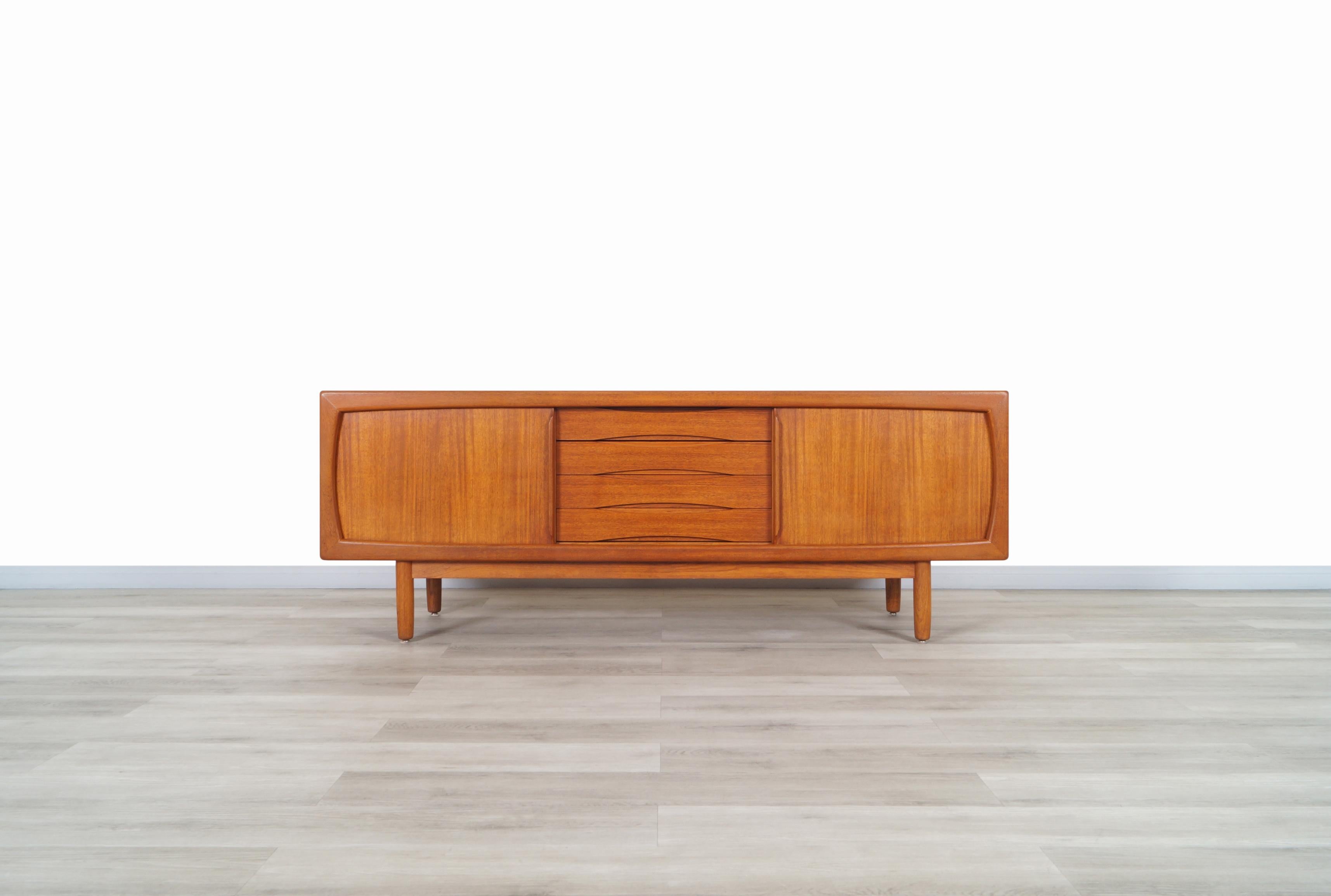 Fabulous Danish modern teak credenza designed and manufactured by H.P. Hansen in Denmark, circa 1960s. This credenza stands out for its elegant teak grains that surround each side of the case, feature two sliding doors at the ends, that when opened,