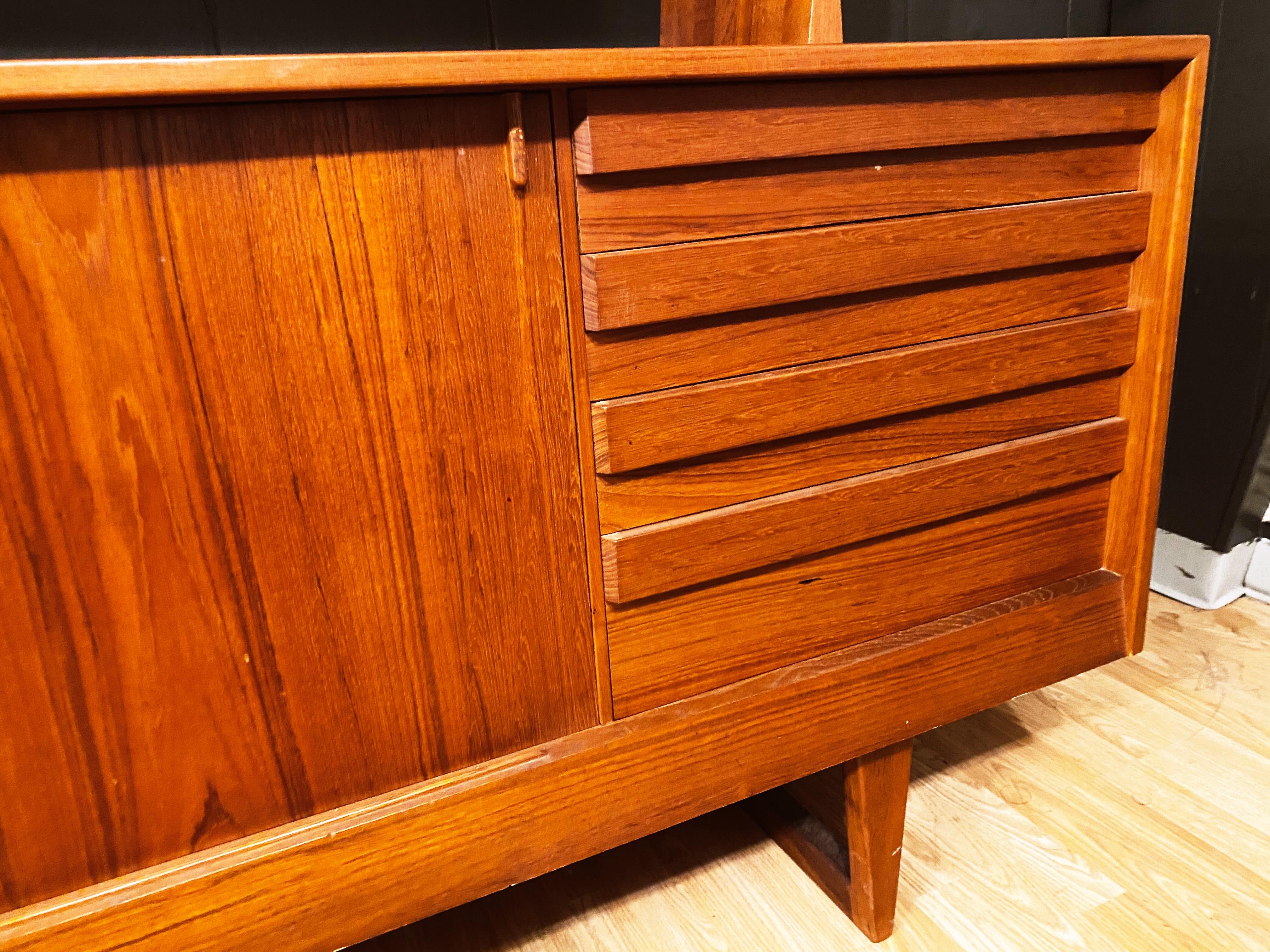This Danish modern teak credenza and removable hutch top by Kurt Ostervig is in overall good condition, with very minor veneer loss along the bottom front (as seen in photos). Sled base. Sliding doors with interior shelving on top and