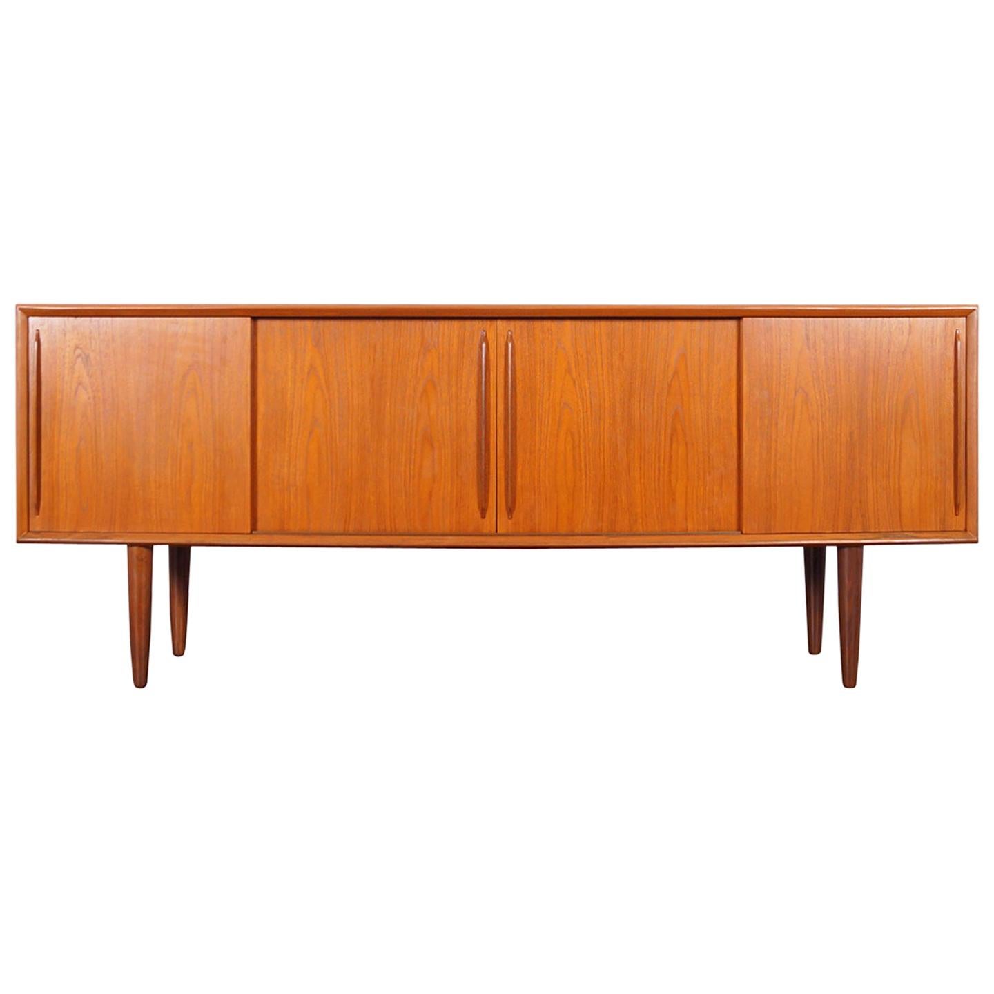 Amazing Danish modern teak credenza designed by Svend A. Larsen for H.P. Hansen in Denmark, circa 1960s. Features four sliding doors with sculptural pulls that open up to three sections. The middle section reveals a large adjustable shelf. On the