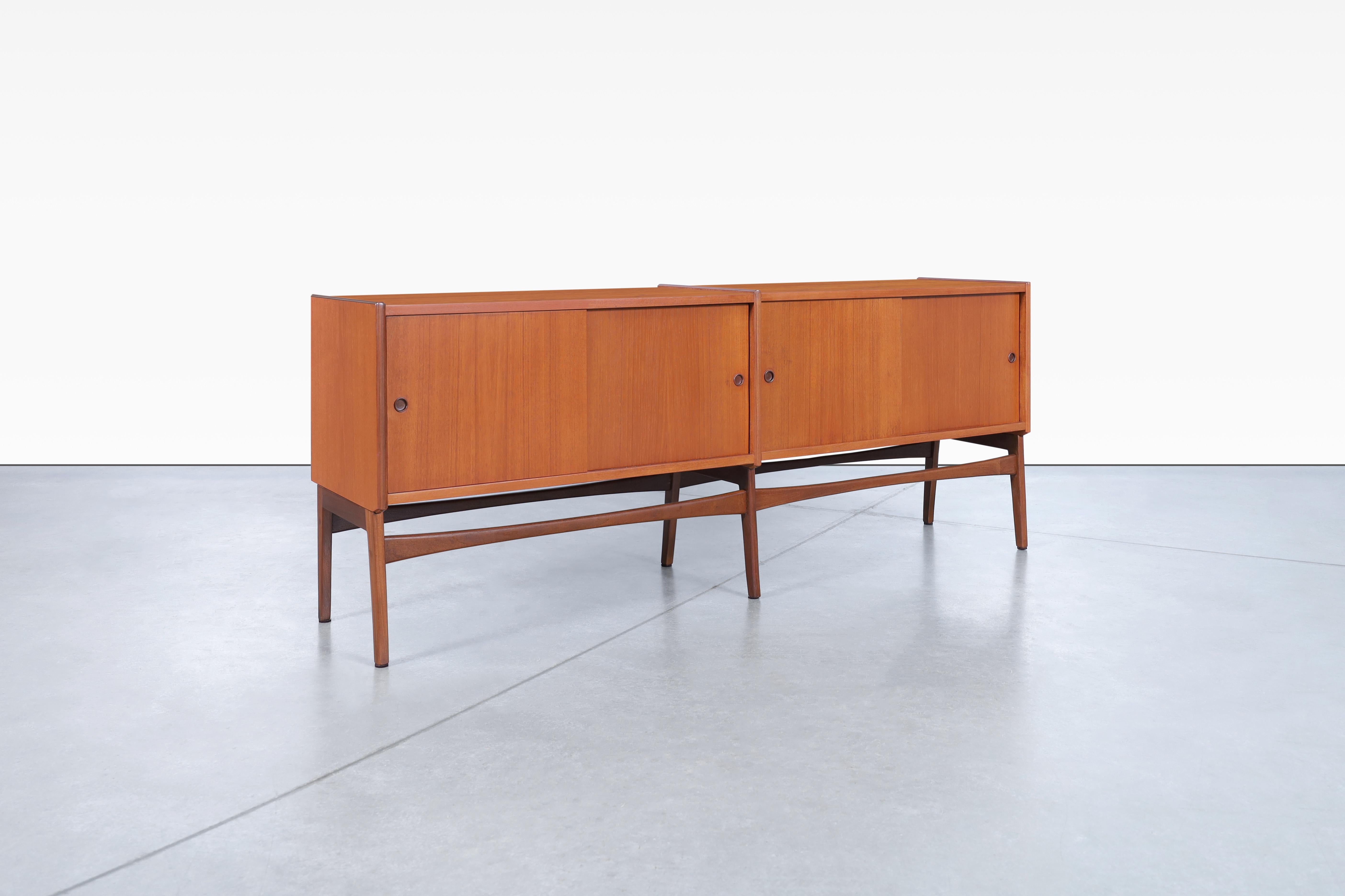Danish modern teak credenza designed in Denmark, circa 1960s. This beautiful refinished piece offers four sliding doors that effortlessly conceal your belongings while adding an element of sleek design to your space. The credenza's angled legs and