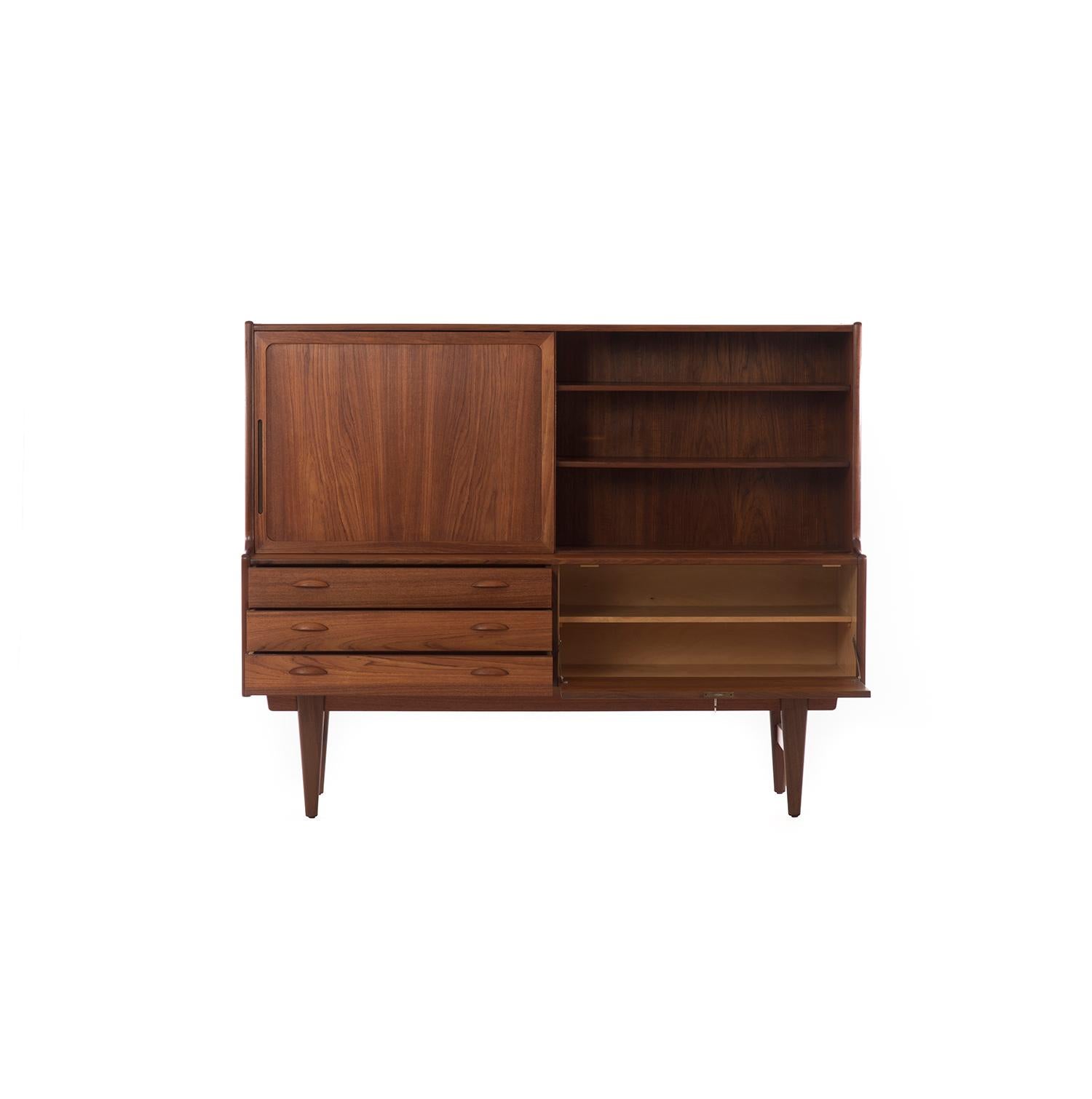 Danish Modern credenza features a drop front door and adjustable shelves. Includes five silver drawers and two larger linen drawers.