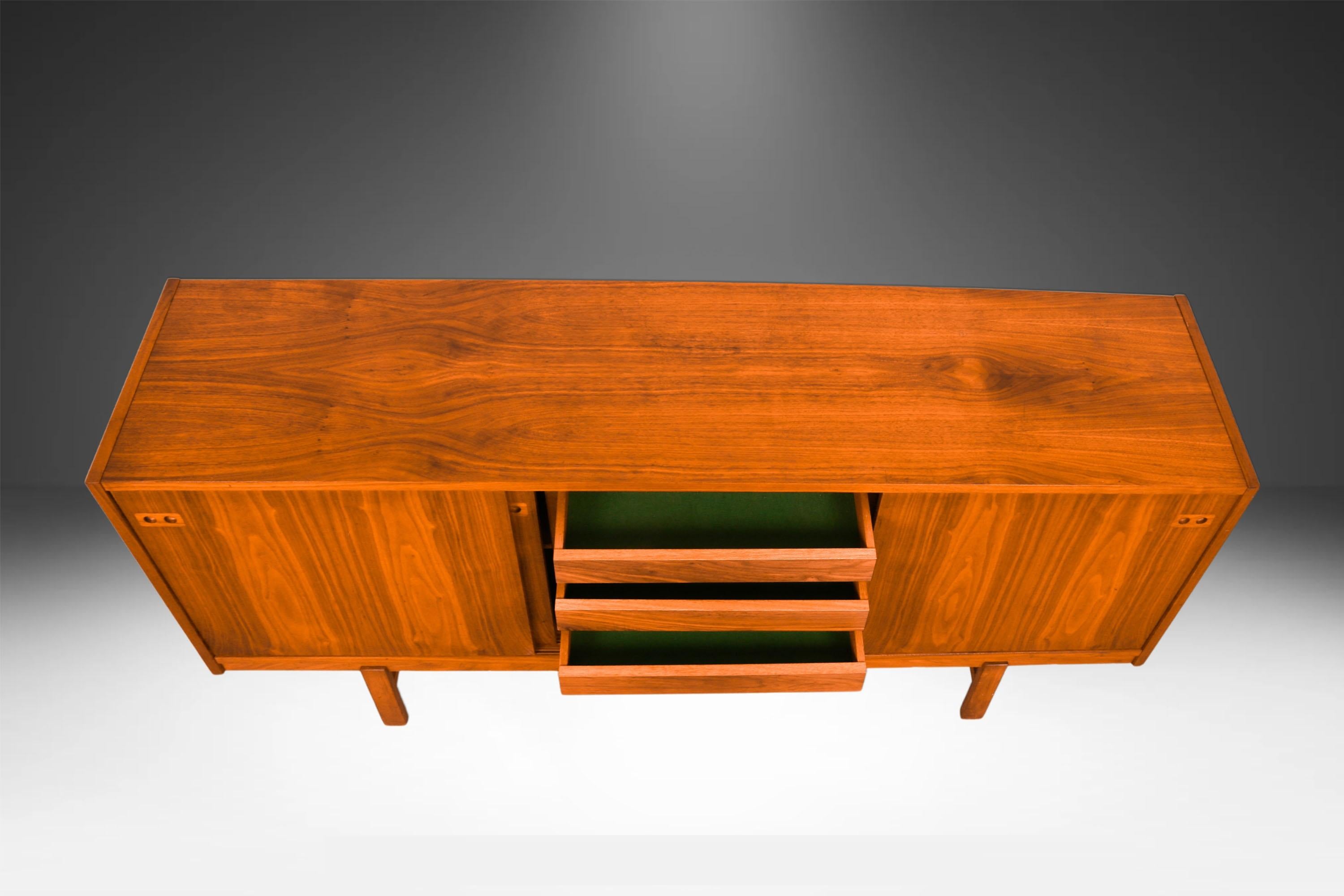 Remarkable, teak, stunning sliding doors, credenza in the style of Kofod-Larsen for Faarup Mobelfabrik made in Denmark. This Danish Modern teak credenza is beautifully embellished with bands of teak running perpendicular to the main surface.