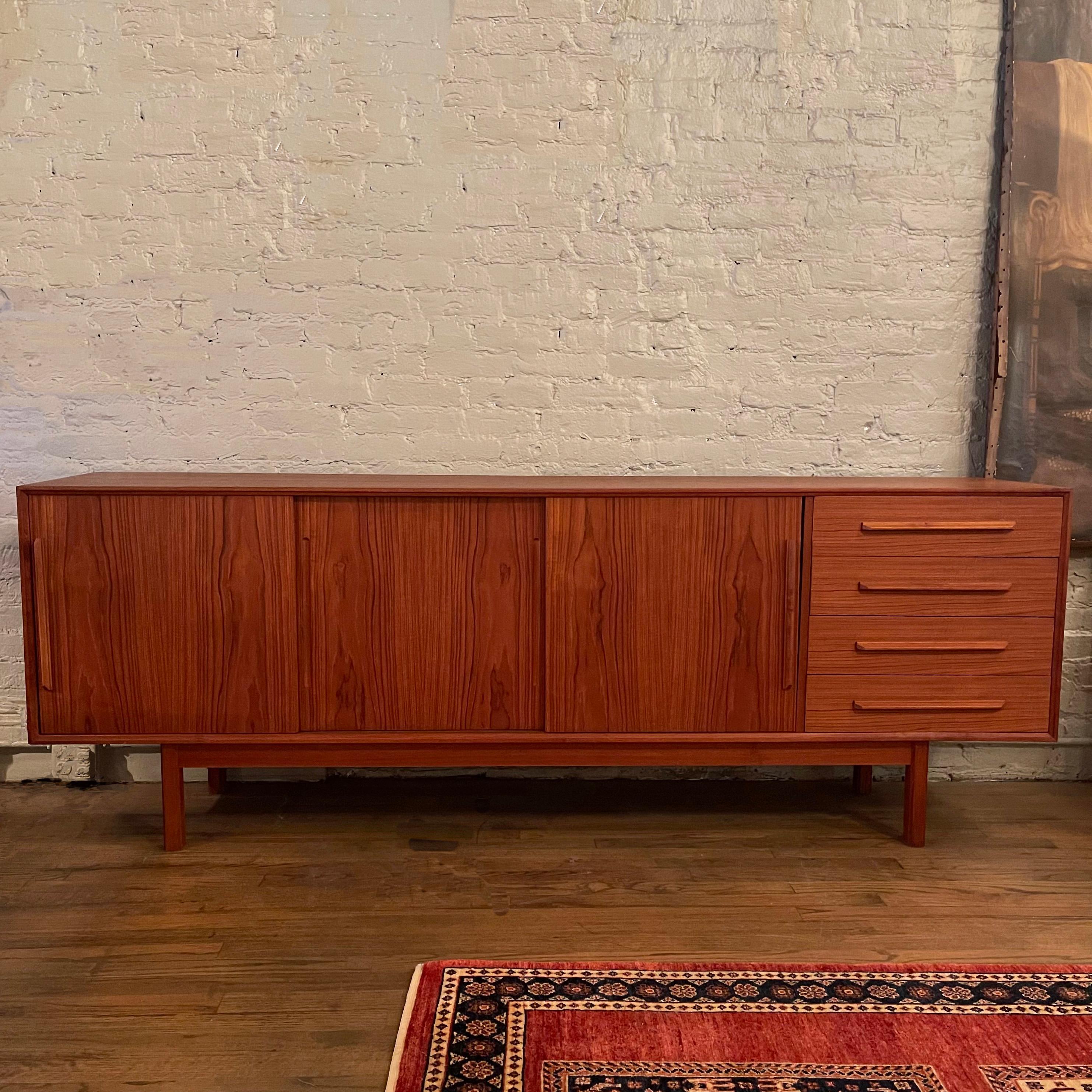 Handsome, streamlined, Scandinavinian modern, teak credenza, sideboard by Dyrlund features sliding doors with interior shelves and hidden drawers and a bank of exterior drawers.