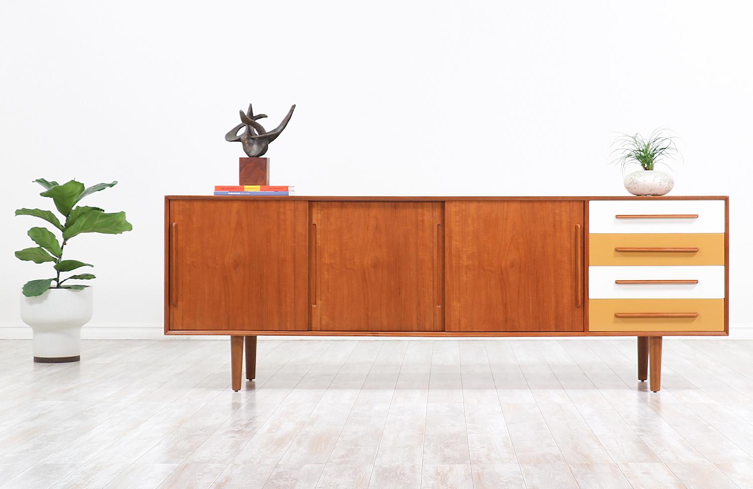 Minimalist modern lacquered credenza designed and manufactured in Denmark circa 1960s. This large Danish Modern credenza features a sturdy teak wood case that sits on four low profile tapered legs showcasing remarkable craftsmanship while ensuring
