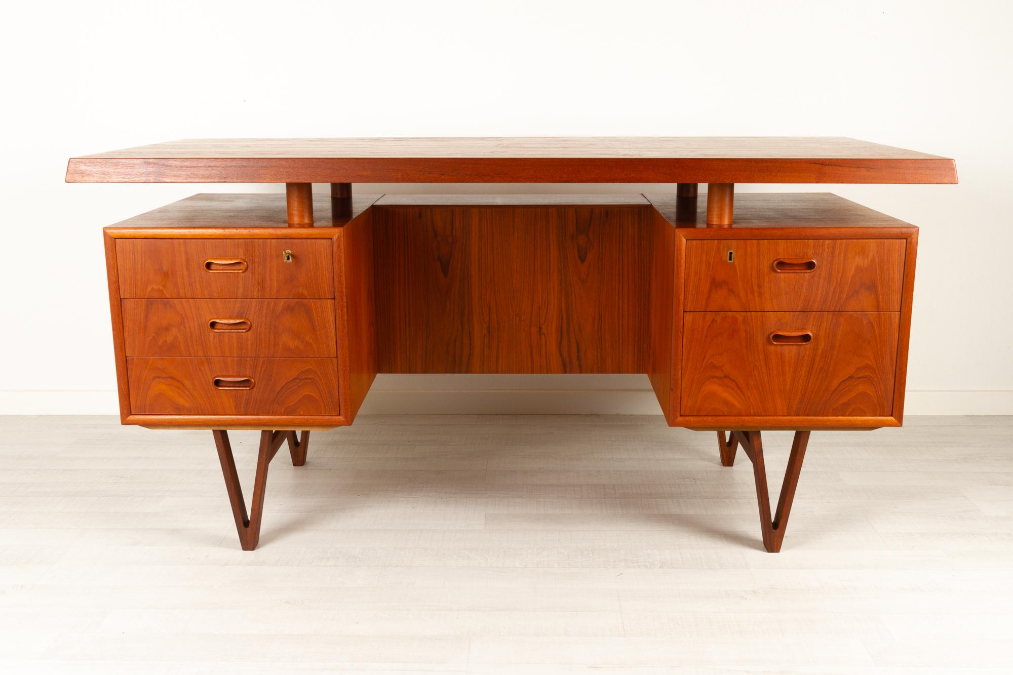 Danish modern teak desk, 1960s
Large Danish Mid-Century Modern executive writing desk in teak. Floating table top resting on four pillars of solid teak. Five drawers, two with lock, key included. Cabinet with drop down door. Standing on V-shaped