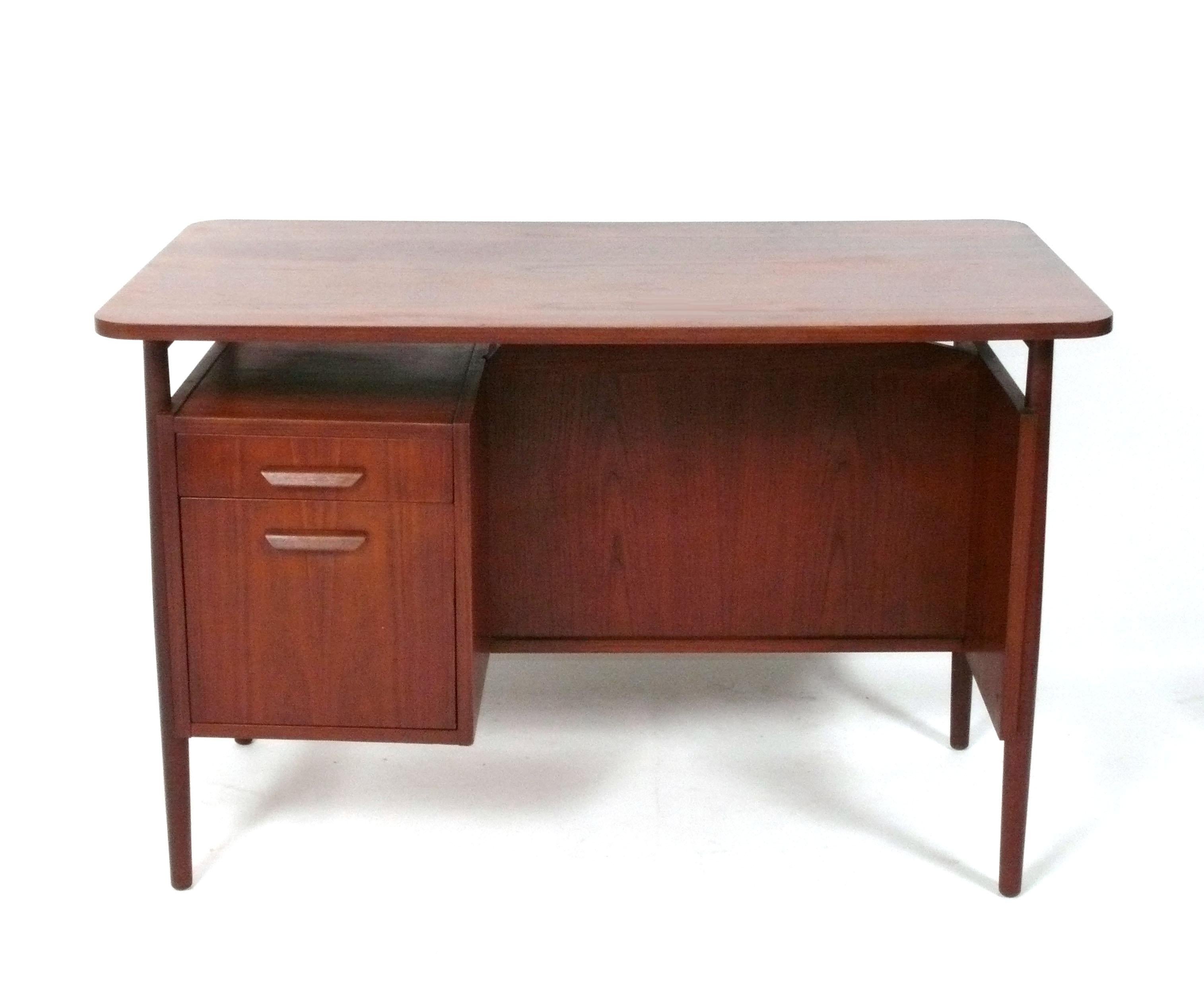 Scrivania danese moderna in teak, disegnata da Gunnar Nielsen Tibergaard Nielsen, Danimarca, anni '60 circa. Ha un sacco di spazio in un ingombro ridotto. A sinistra c'è uno scaffale con sotto un piccolo cassetto per penne e simili, mentre sotto c'è