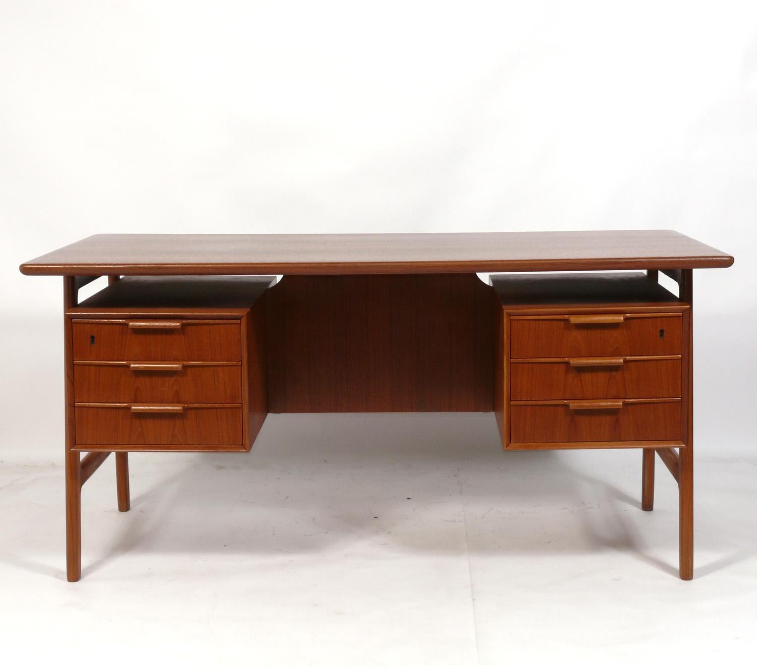Clean lined Danish modern teak desk, designed by Gunni Omann for Jun Mobelfabrik, Denmark, circa 1960s. It has recently been refinished and is ready to use. Wonderful design that is finished on both sides with bookshelves and a cabinet on the back