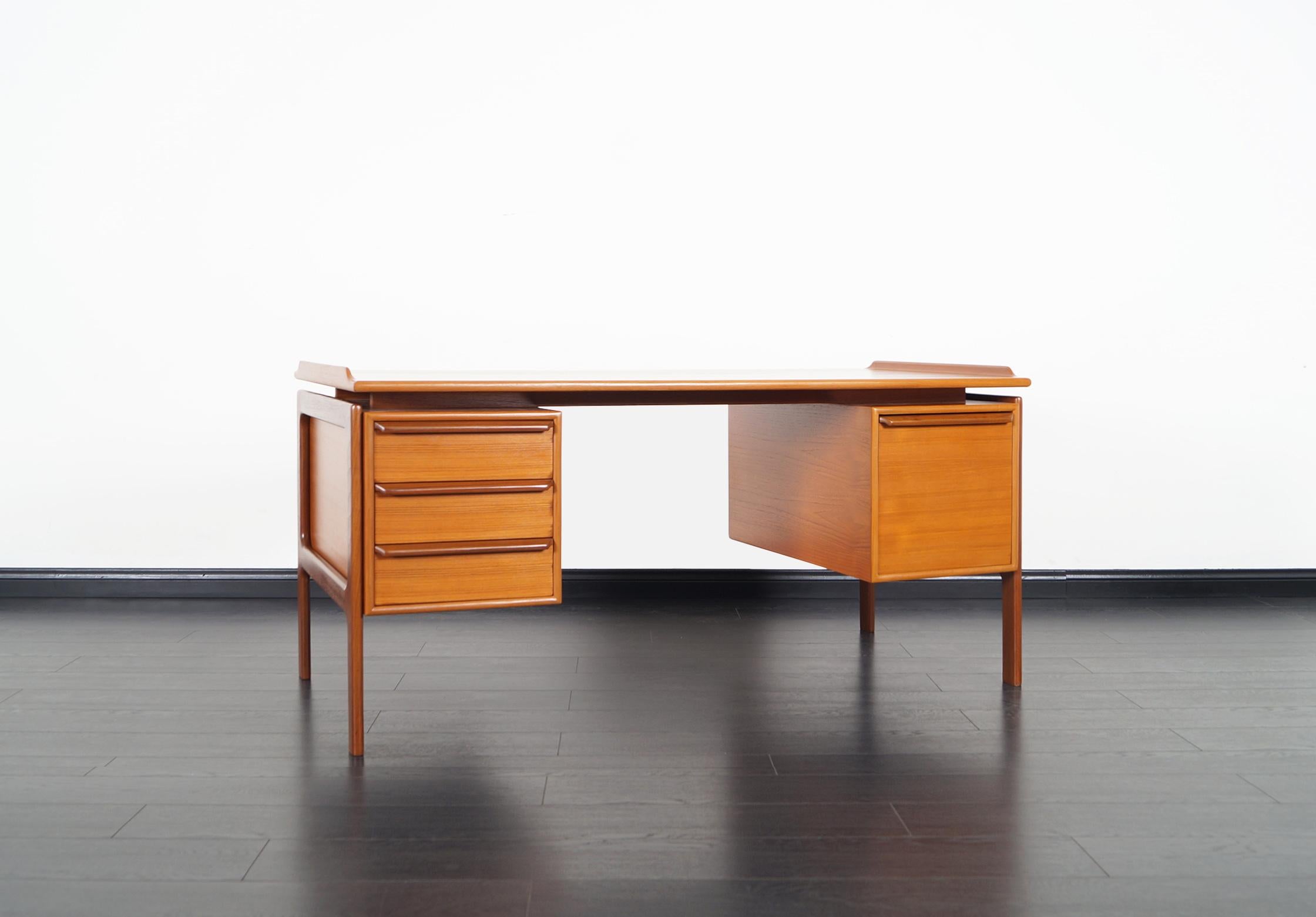Danish modern teak desk manufactured by G.V. Møbler in Denmark, circa 1960s. The top has a floating top appearance. It features three drawers on the left and a file drawer on the right. Nice details are the dovetailed joints and clean lines.