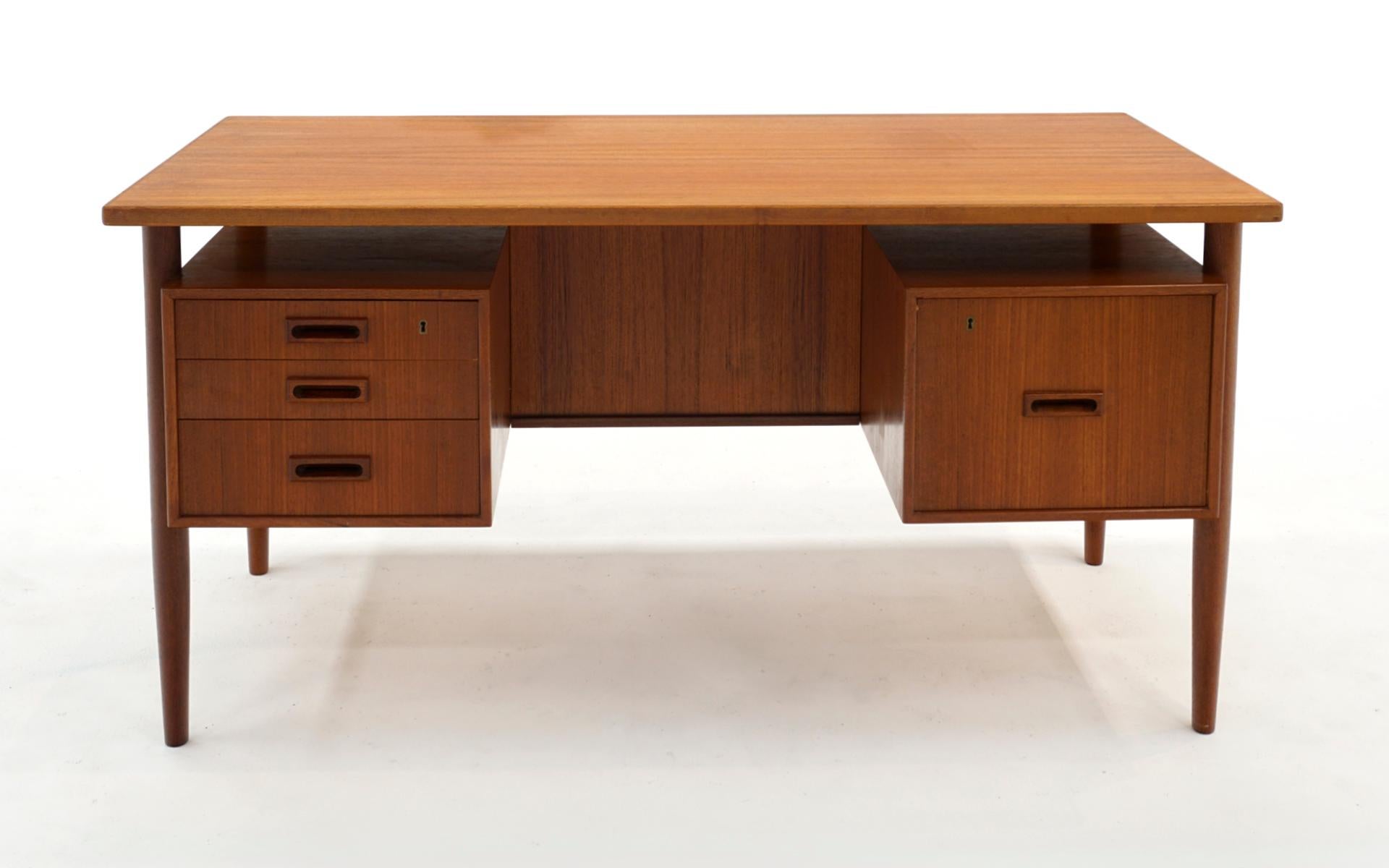 Mid-Century Danish Modern teak desk with a floating top and bookcase front. Three drawers on the left and one large file drawer on the right. This was acquired from the original owner who purchased it in the 1960s when living in Europe. It is in
