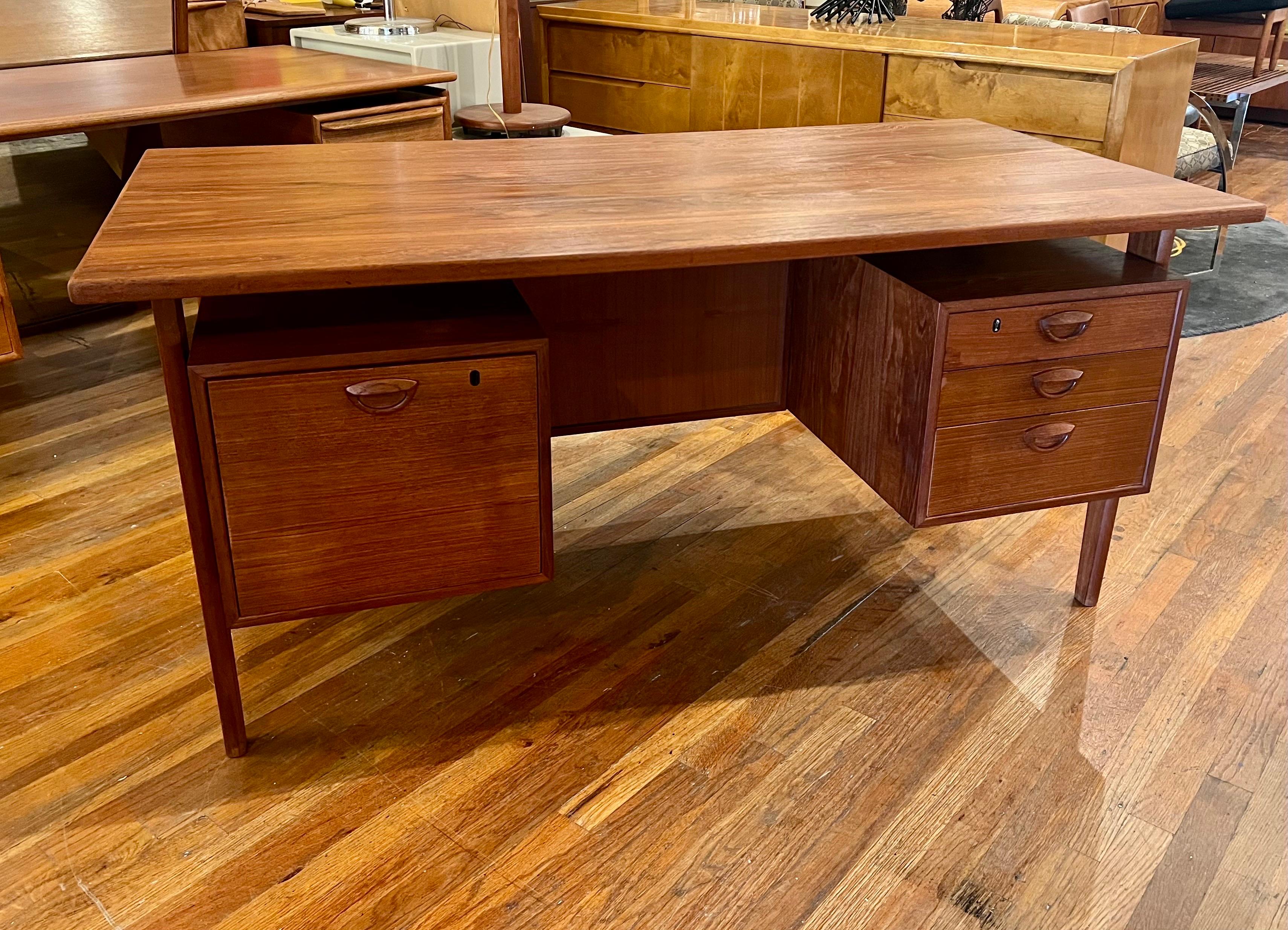 A gorgeous teak executive desk with a floating top, model FM59, designed by architect Kai Kristiansen for Feldballes Mobelfabrik. The top of the Scandinavian writing table floats over a box with a pull-out tray and a large filing drawer on the
