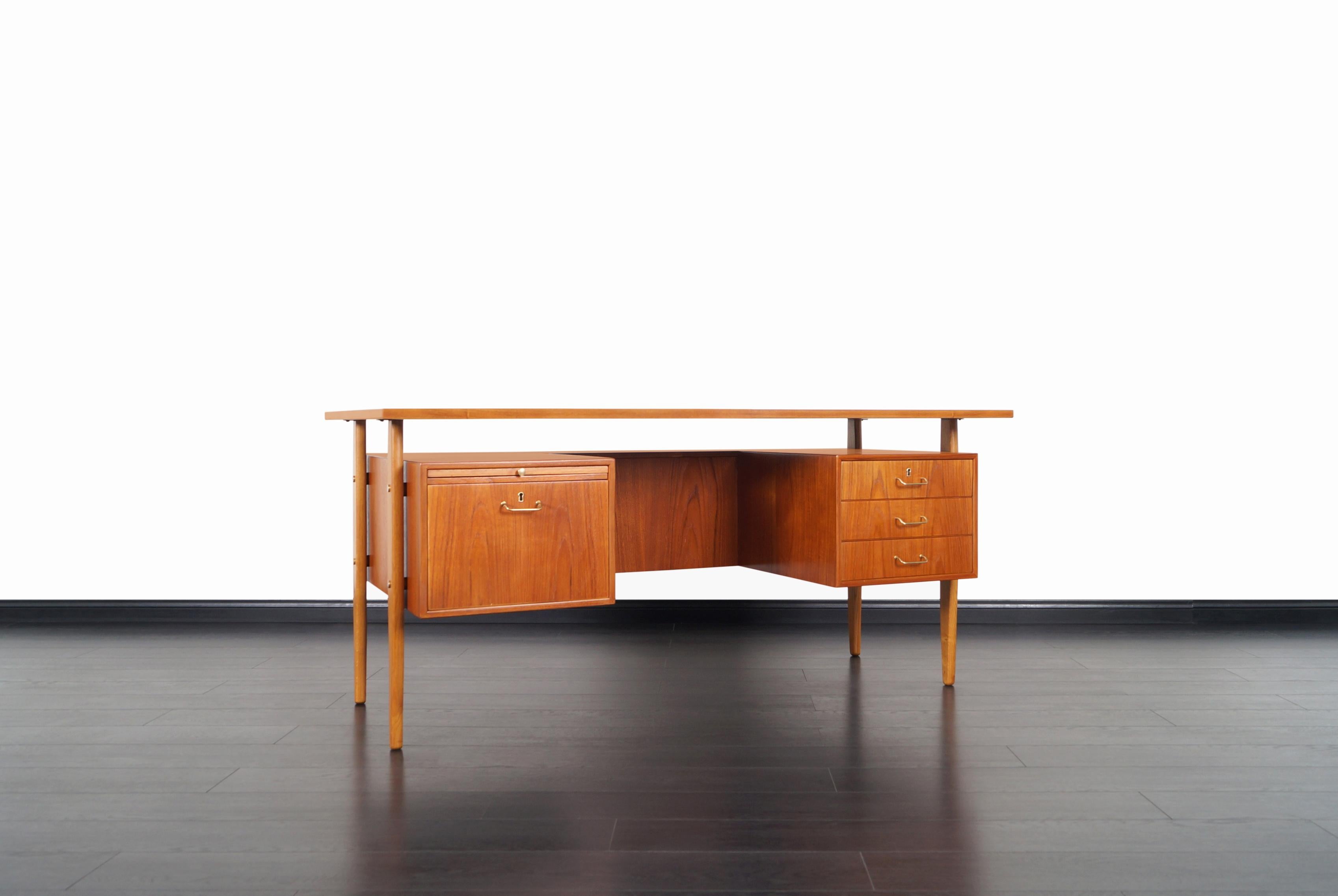 Amazing Danish modern teak desk designed by Torben Strandgaard for Falster Møbelfabrik. Standing out by its design features a floating top design, it includes three drawers on the right side and a file drawer with a pull-out writing surface on the