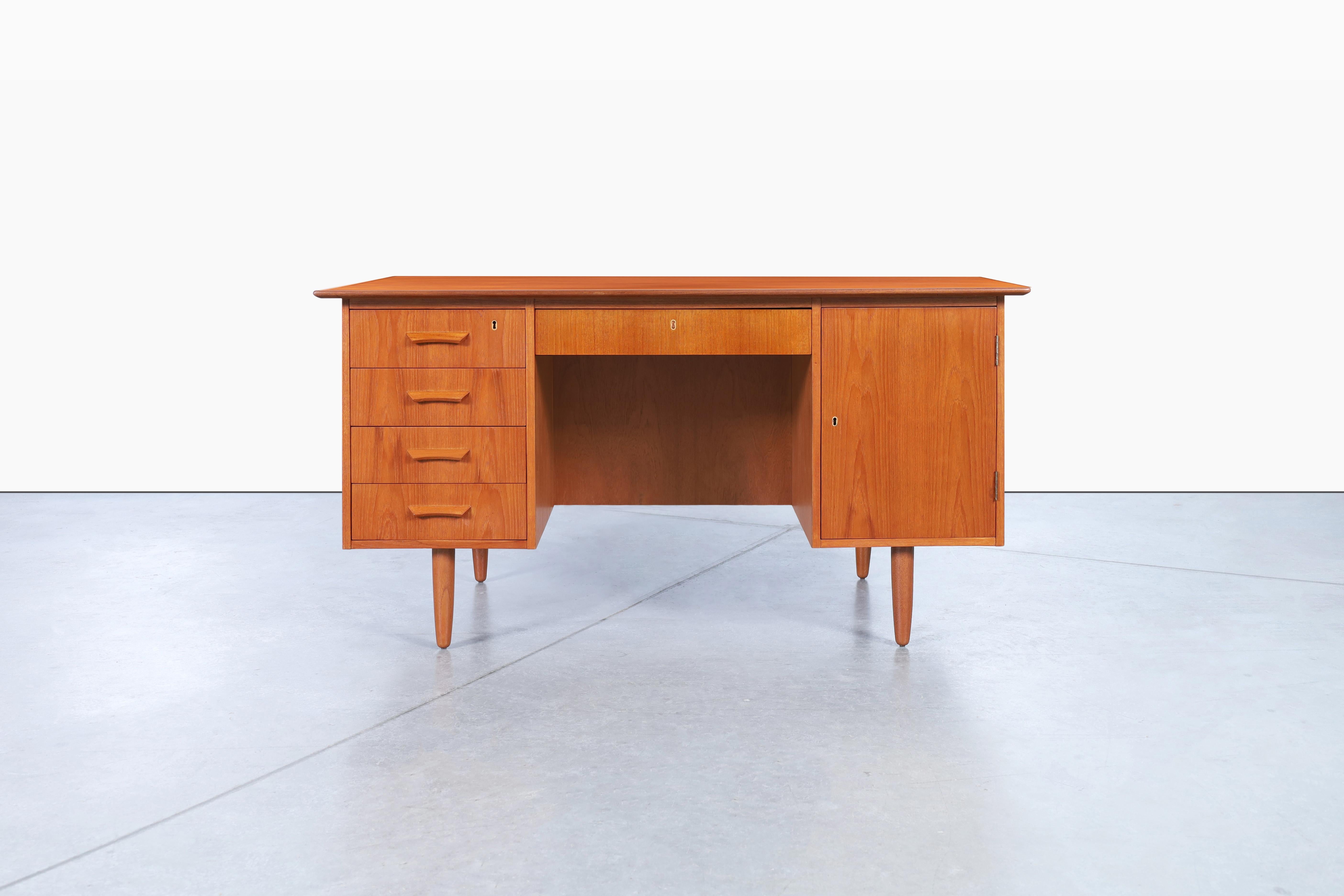 Stunning Danish modern teak desk designed in Denmark, circa 1960s. This desk features four dovetail drawers and a generous compartment, providing ample storage for all your essentials. Each drawer and the handcrafted handles add a personal touch of