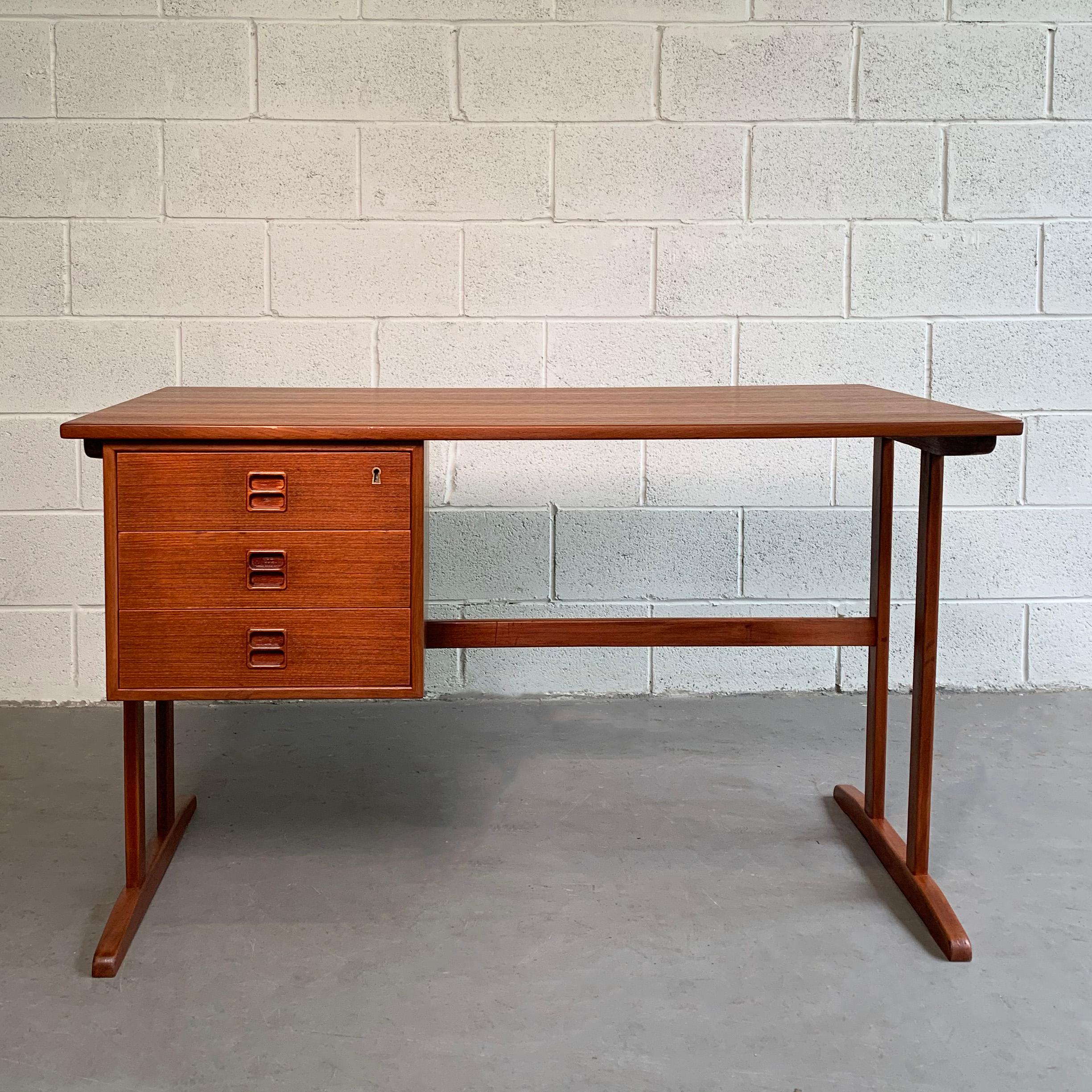 Danish modern, teak desk with 3 drawers features a trestle base with sled legs and is finished on the back with an open cubby book or display shelf.
