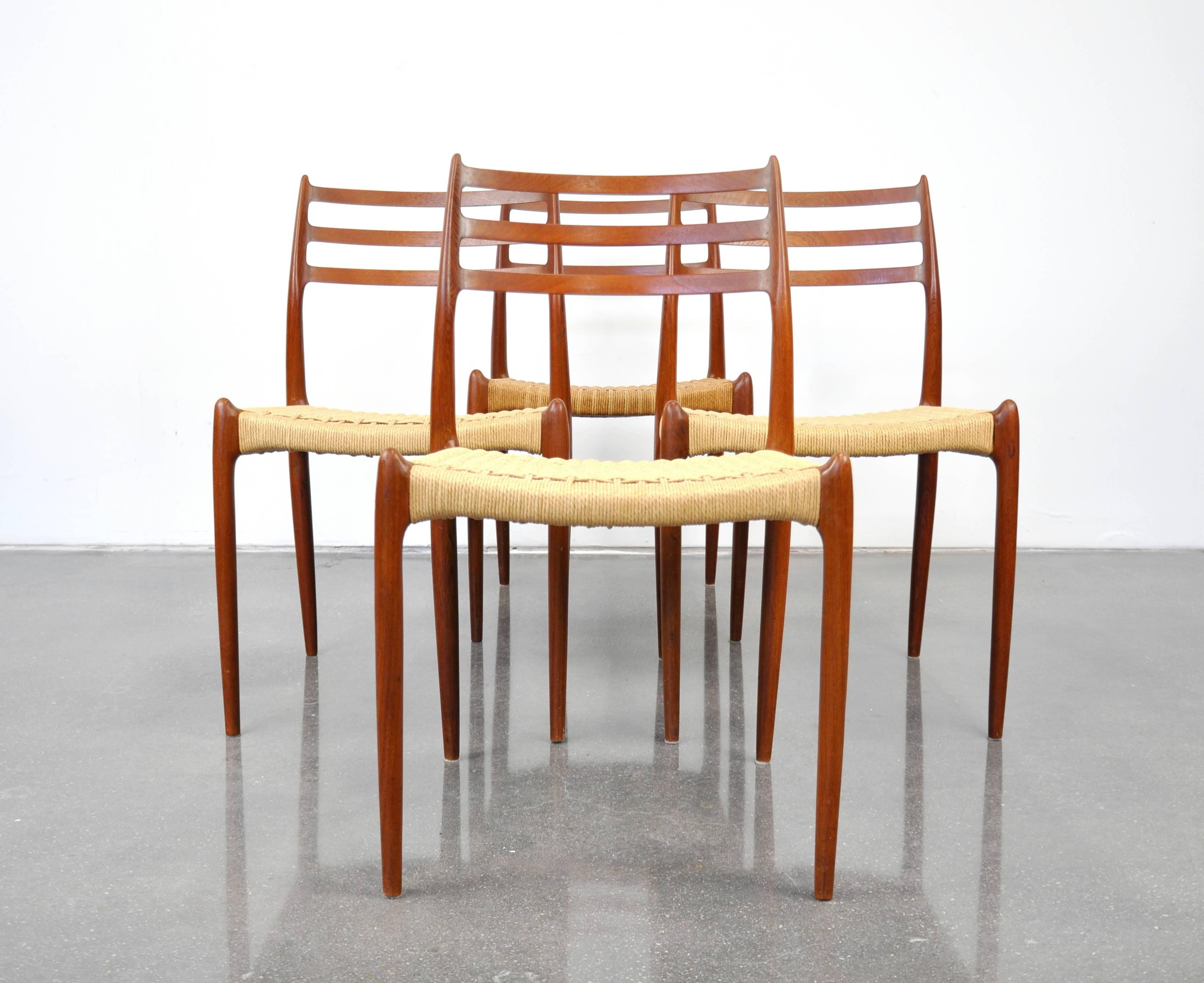 A vintage Mid-Century Modern teak dining set including a professionally restored draw-leaf extension dining table and a set of four model #78 chairs designed by Niels Otto Moller for J.L. Mollers Mobelfabrik in Denmark, dating from the 1960s. The