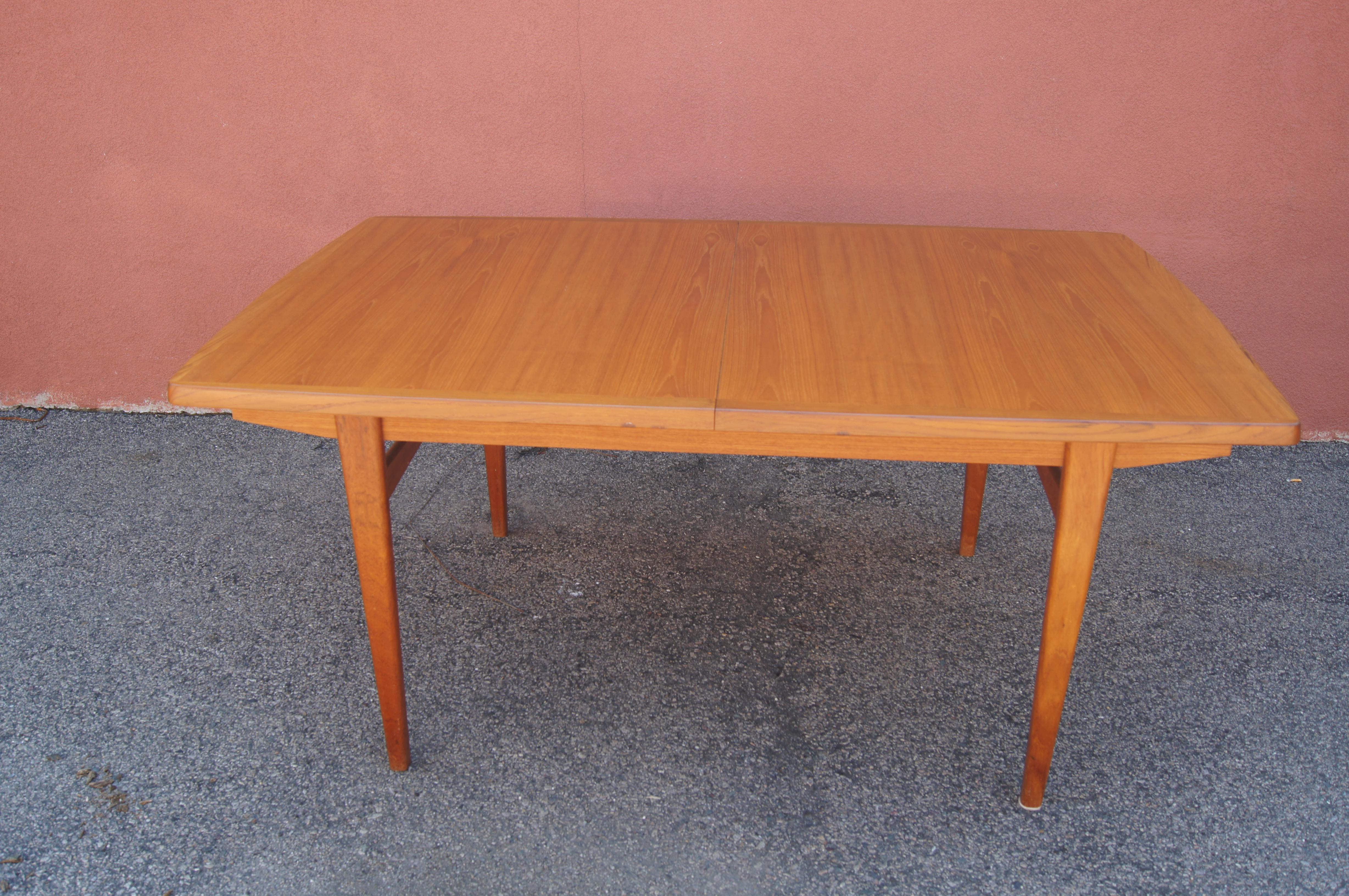 A classic example of Danish modern design, this teak dining table sets a rounded-edge top on tapered legs. Two leaves accommodate extra seating.

The dimensions below reflect the table without its extensions; the 18-inch-wide leaves extend the table