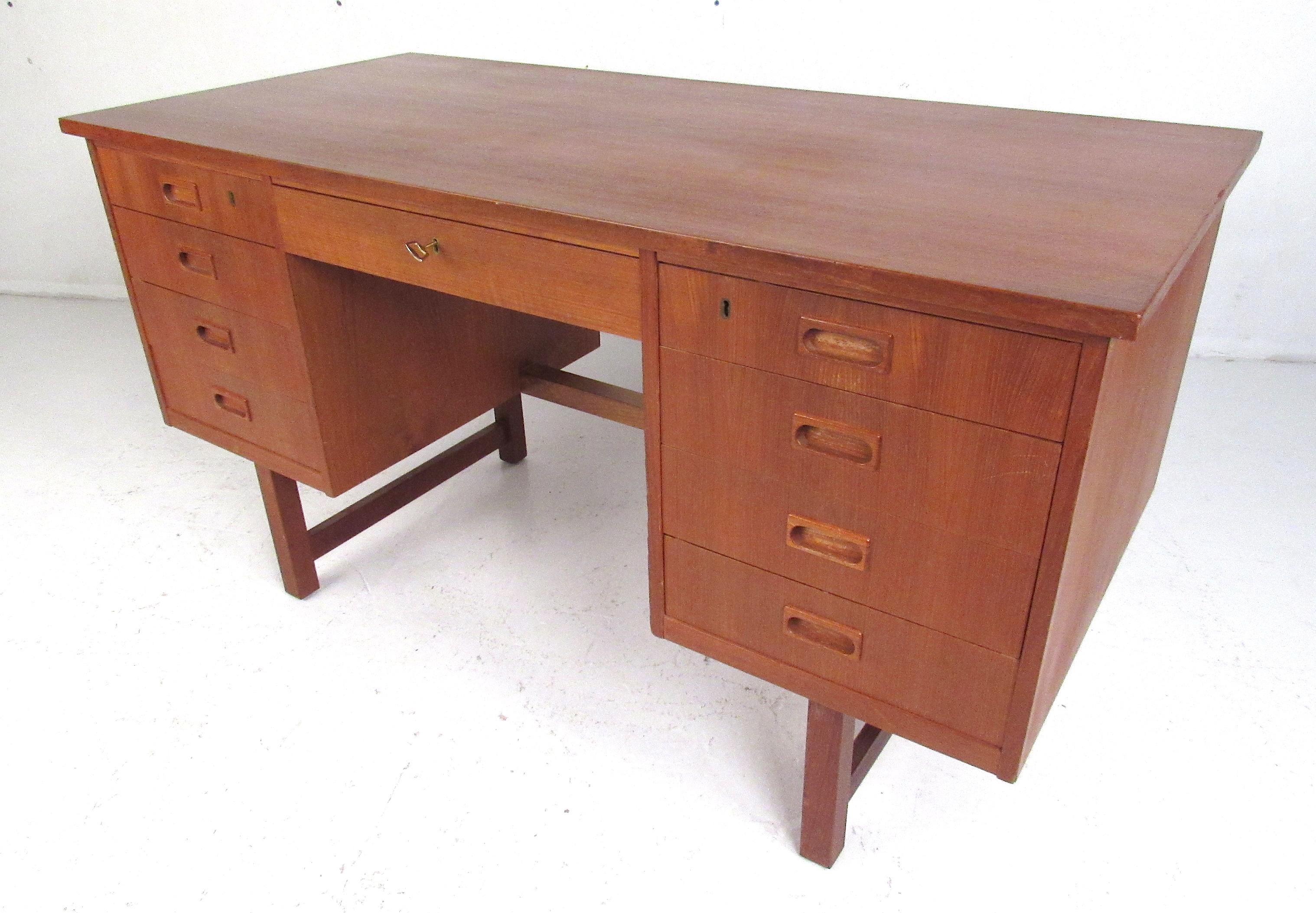 Classic desk from the 1970s, minimalist Danish design. Teak veneer, recessed pulls, nine drawers with top three locking, finished back. Key supplied. Please confirm item location (NY or NJ) with dealer.
