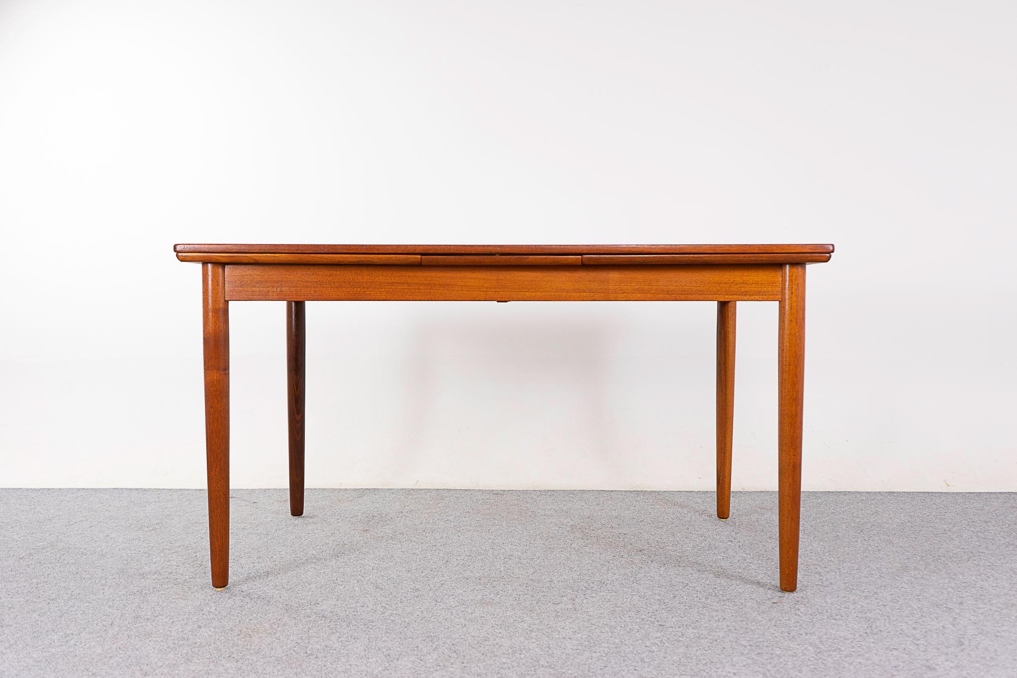 Teak draw leaf dining table, circa 1960's. Self-storing leaves slide out from each end to expand the table surface by nearly two times, versatile! Sleek tapering elegant legs. A beautiful combination of solid wood edges and center panels with