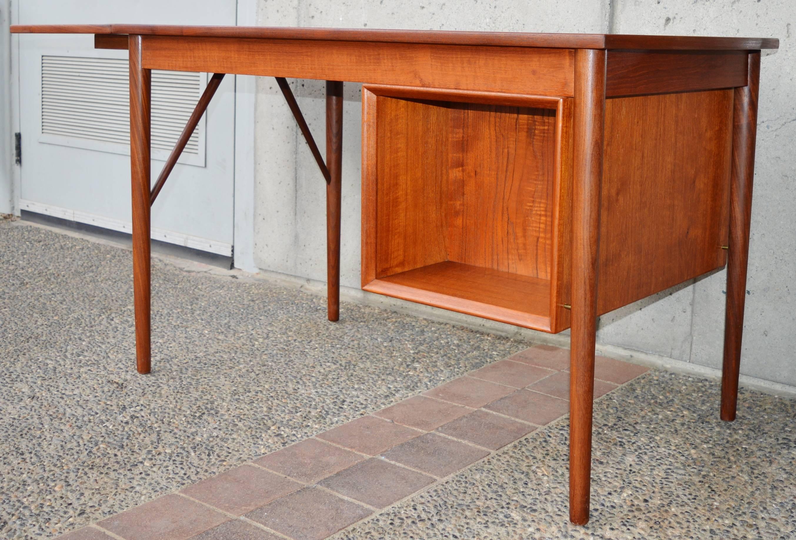 This stunning Danish modern teak top quality desk was designed by EW Bach for Oddense Maskinsnedkeri A-S in the 1960s. Featuring a darker toned edge trim and legs, and a rich patina throughout. The front features a bank of three drawers with a