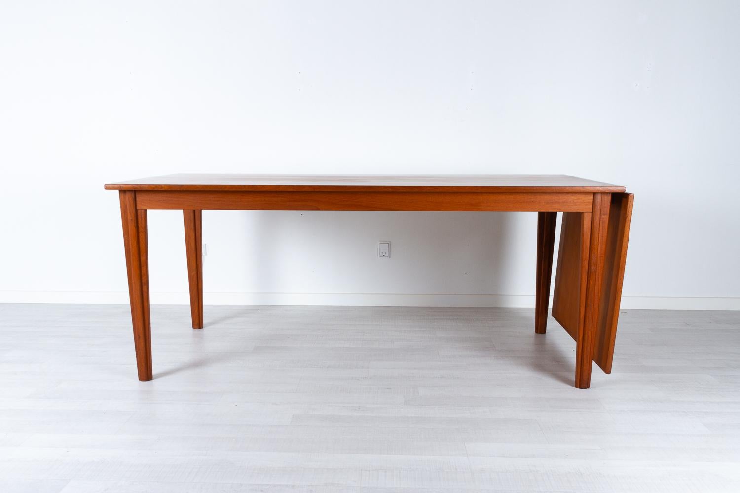 Danish modern teak drop leaf dining table, 1960s
Large dining table with drop leaf extension. Extension leaf can hang on one end or be stored under the table top. Table top slides very easily and can be operated by one person with ease. Tapered legs