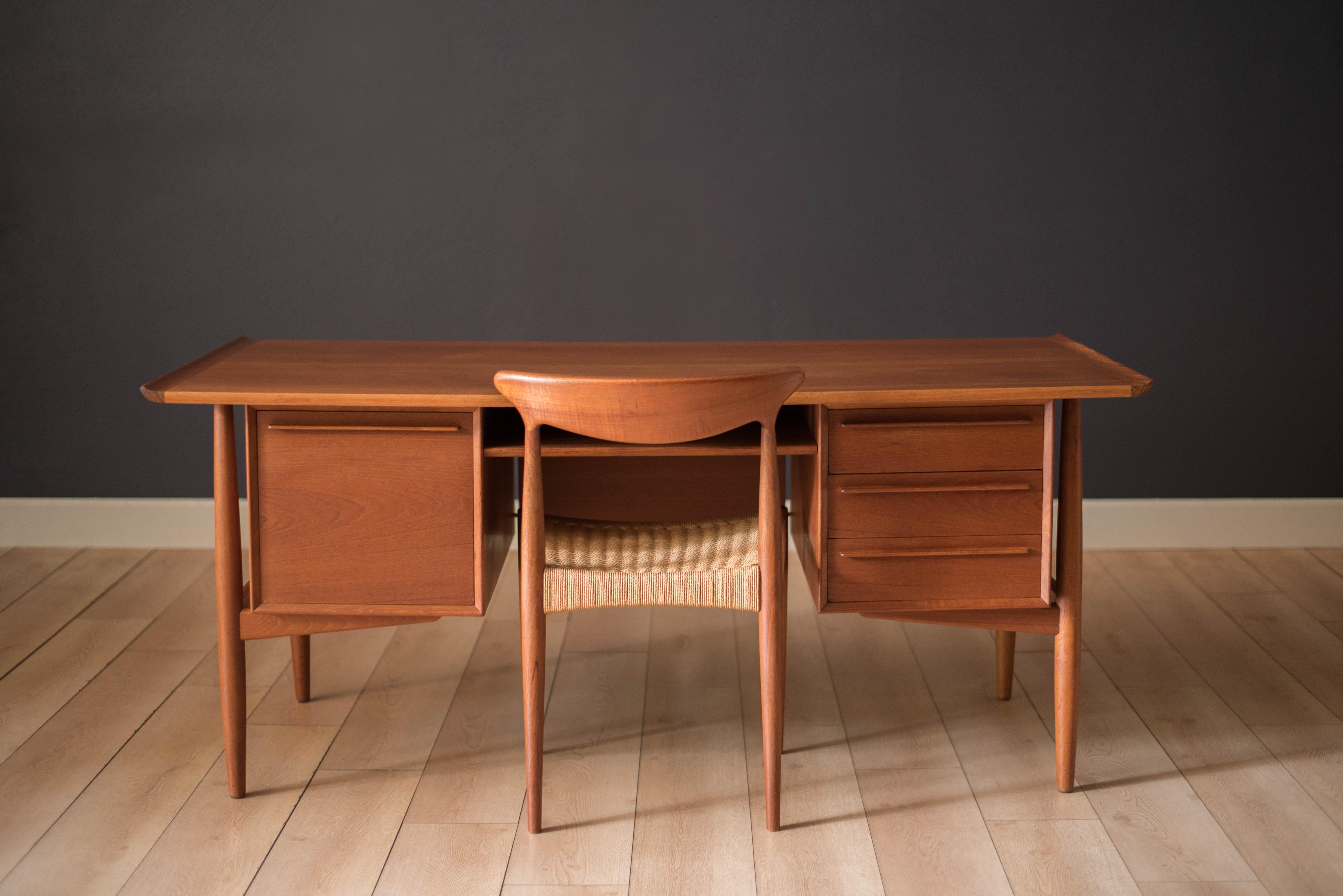 Mid century executive desk in teak manufactured by H.P. Hansen, Denmark, circa 1960s. Features a raised sculpted top and floating external legs. This versatile desk can be showcased from all angles and includes a backside bookshelf compartment with