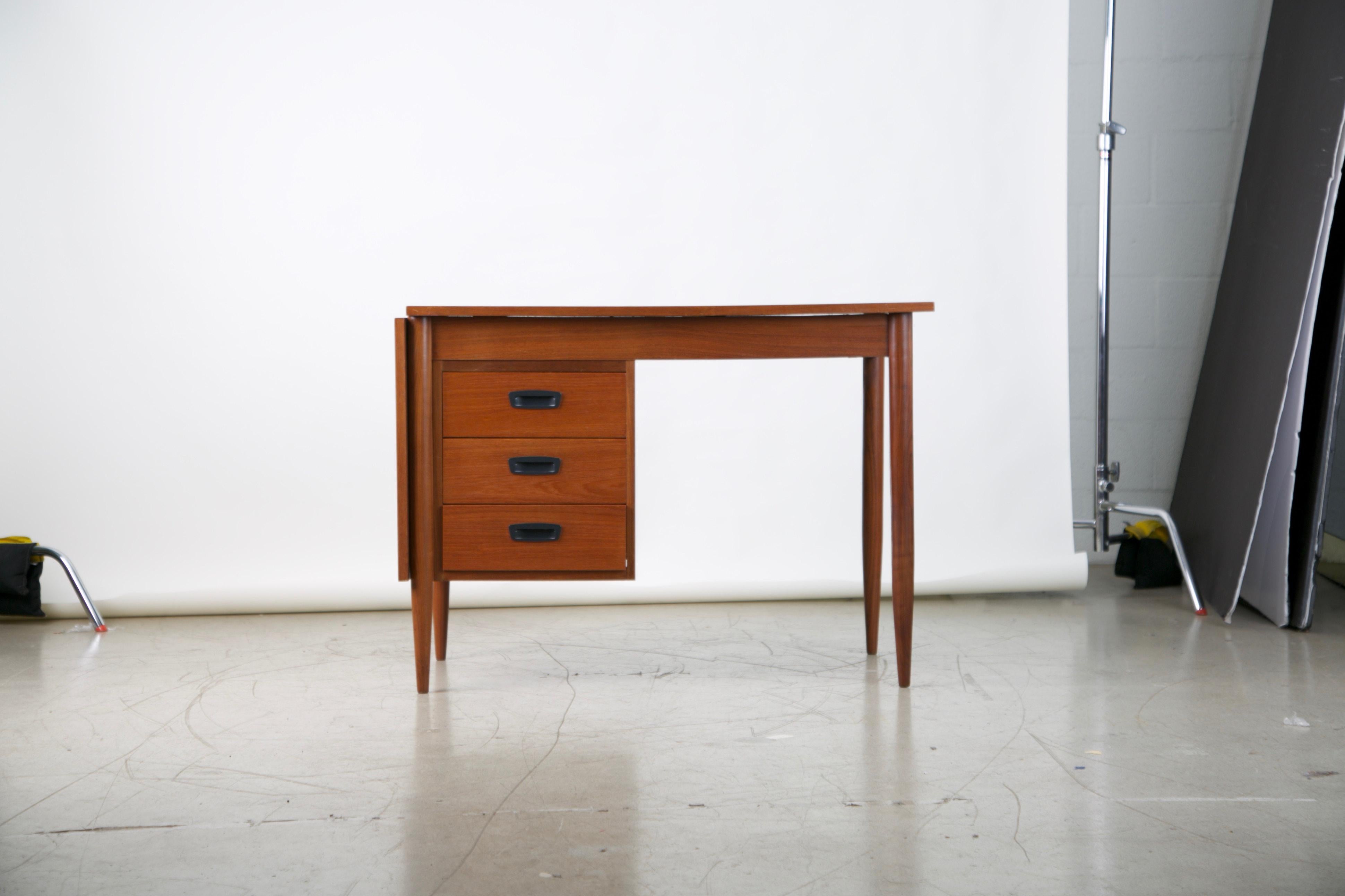 Elegantly designed Danish modern teak expandable drop-leaf desk. Fabricated from teak which displays an admirable grain with a variety of movement. This compact desk is perfect for an interior which is tight on space. Featuring slender proportions