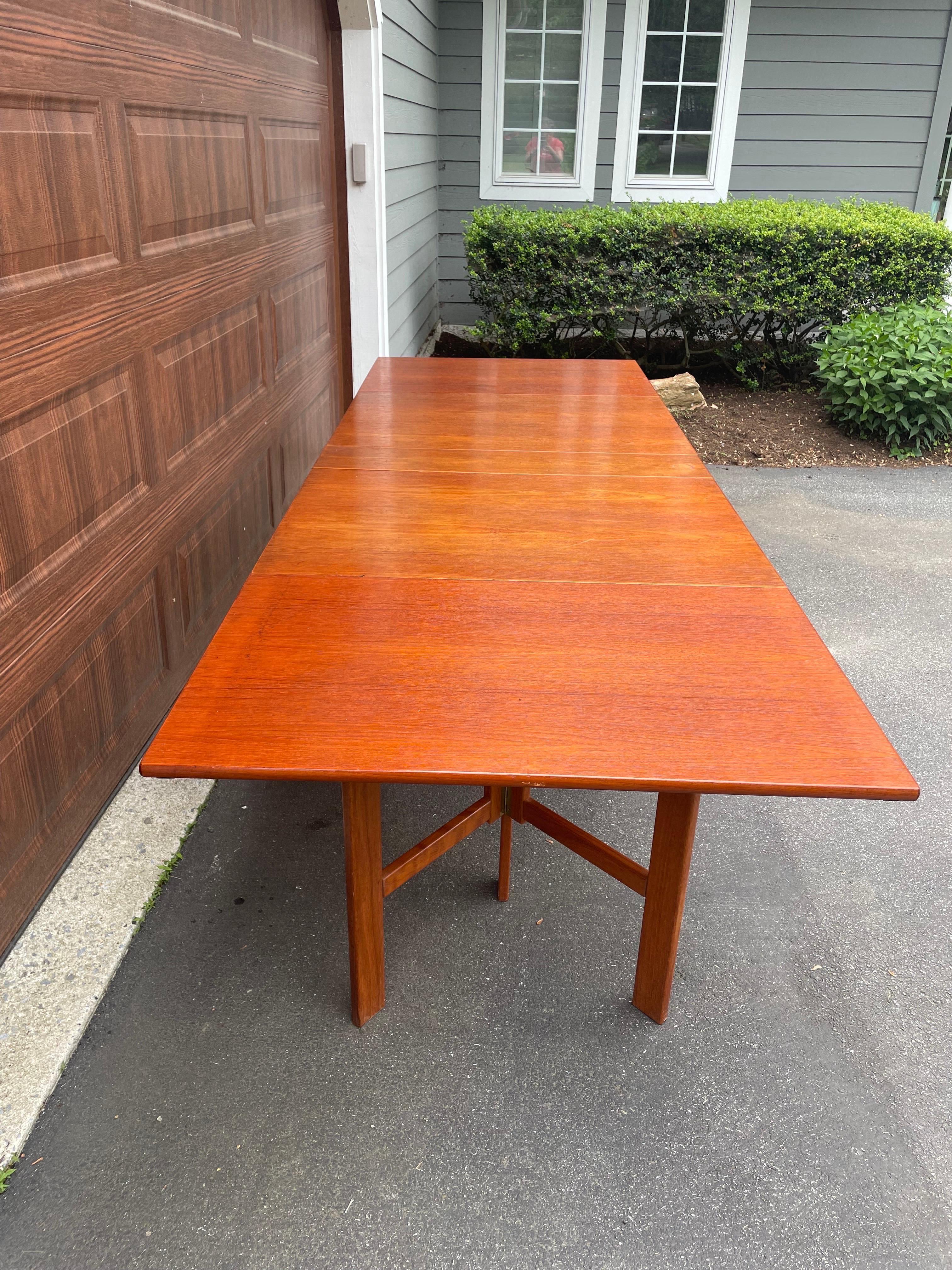 Gorgeous teak danish modern dining table! Expands to over 110” ( 9+ feet!) on fold - out gatelegs, yet folds down into a lovely console measuring just over 8” - neat trick! Integrated levelers (see photos) create a stable surface on this big table.