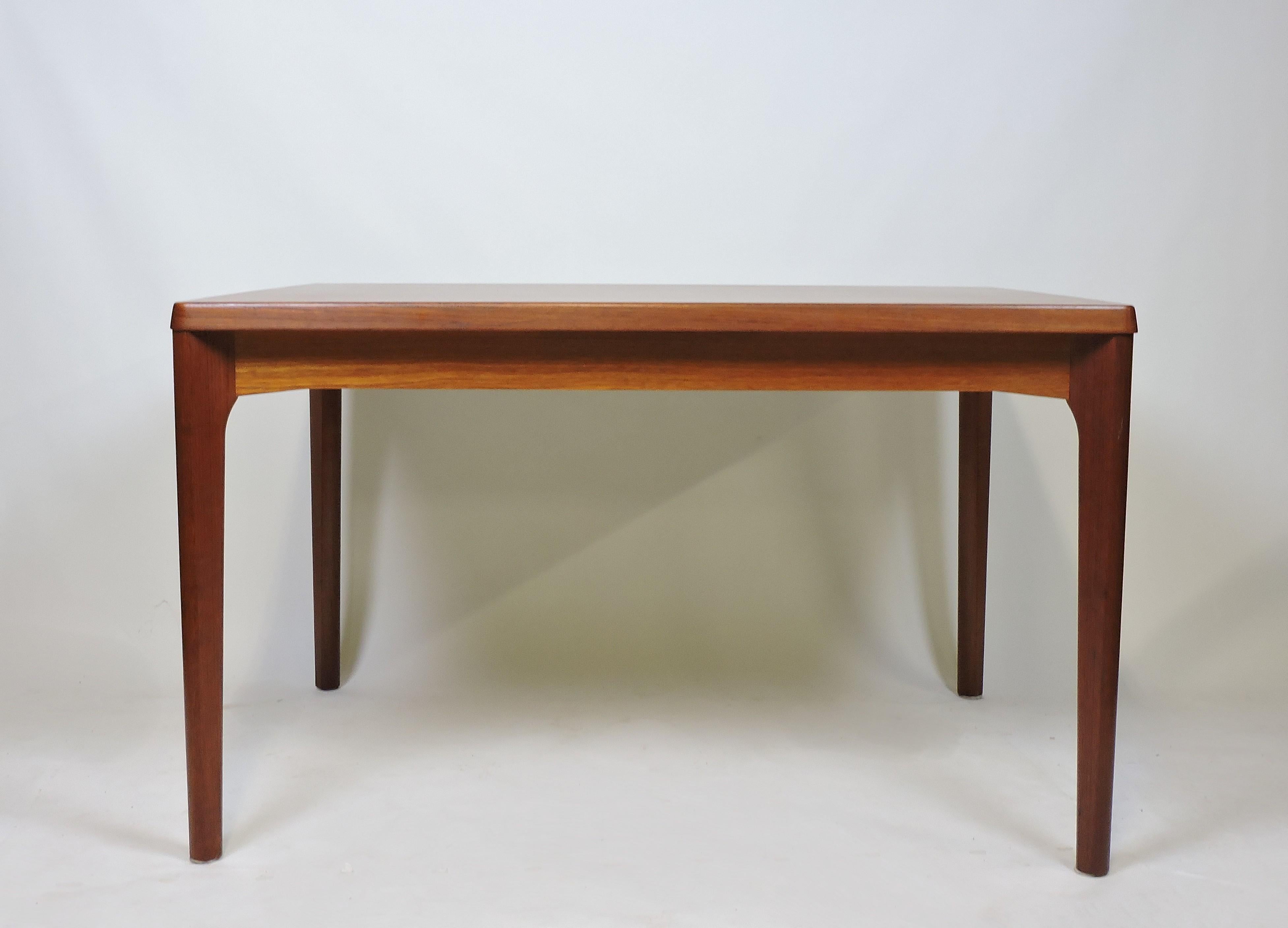 Simple and elegant dining table designed by Henning Kjaernulf and manufactured in Denmark by Vejle Stole. This table has sculpted solid teak legs and two hidden leaves that can extend the table to 82 1/2 inches. Stamped underneath.
 