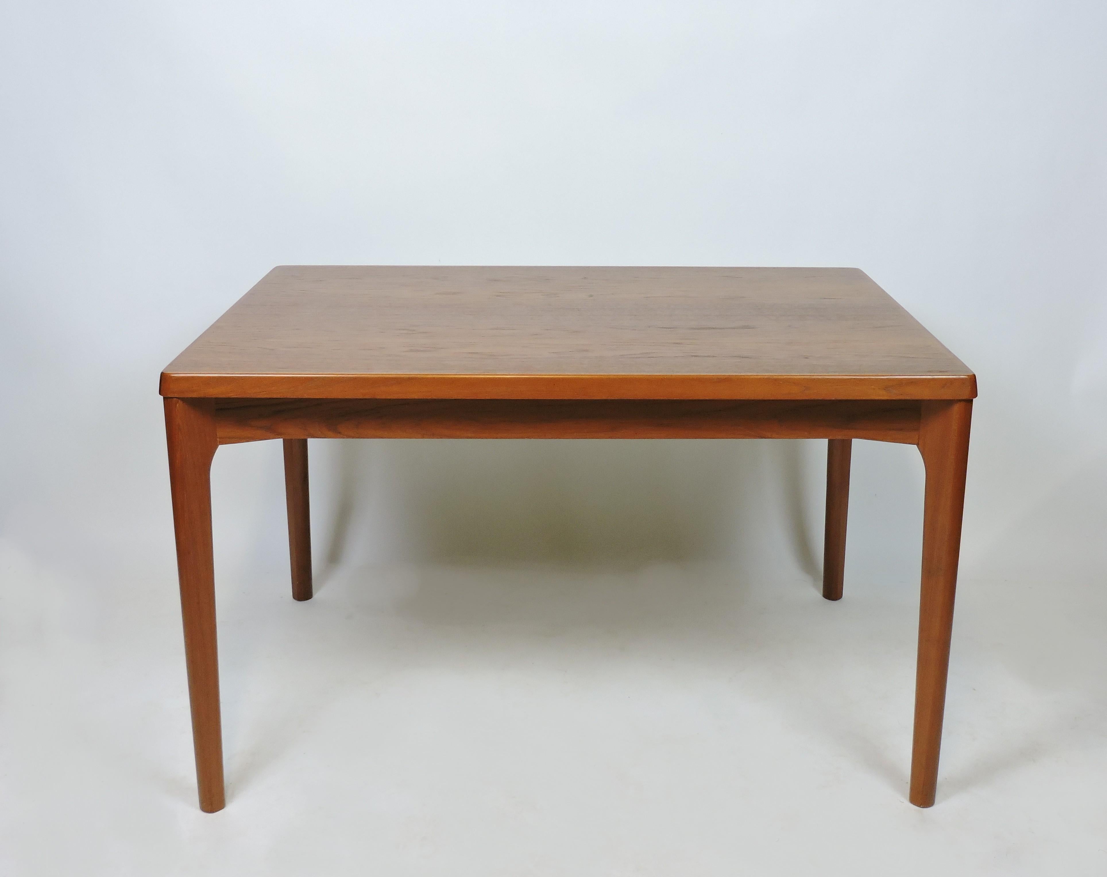 Simple and elegant dining table designed by Henning Kjaernulf and manufactured in Denmark by Vejle Stole. This table has beautiful wood grain, sculpted solid teak legs, and two hidden leaves that can extend the table from 47 inches to 82 1/2 inches.