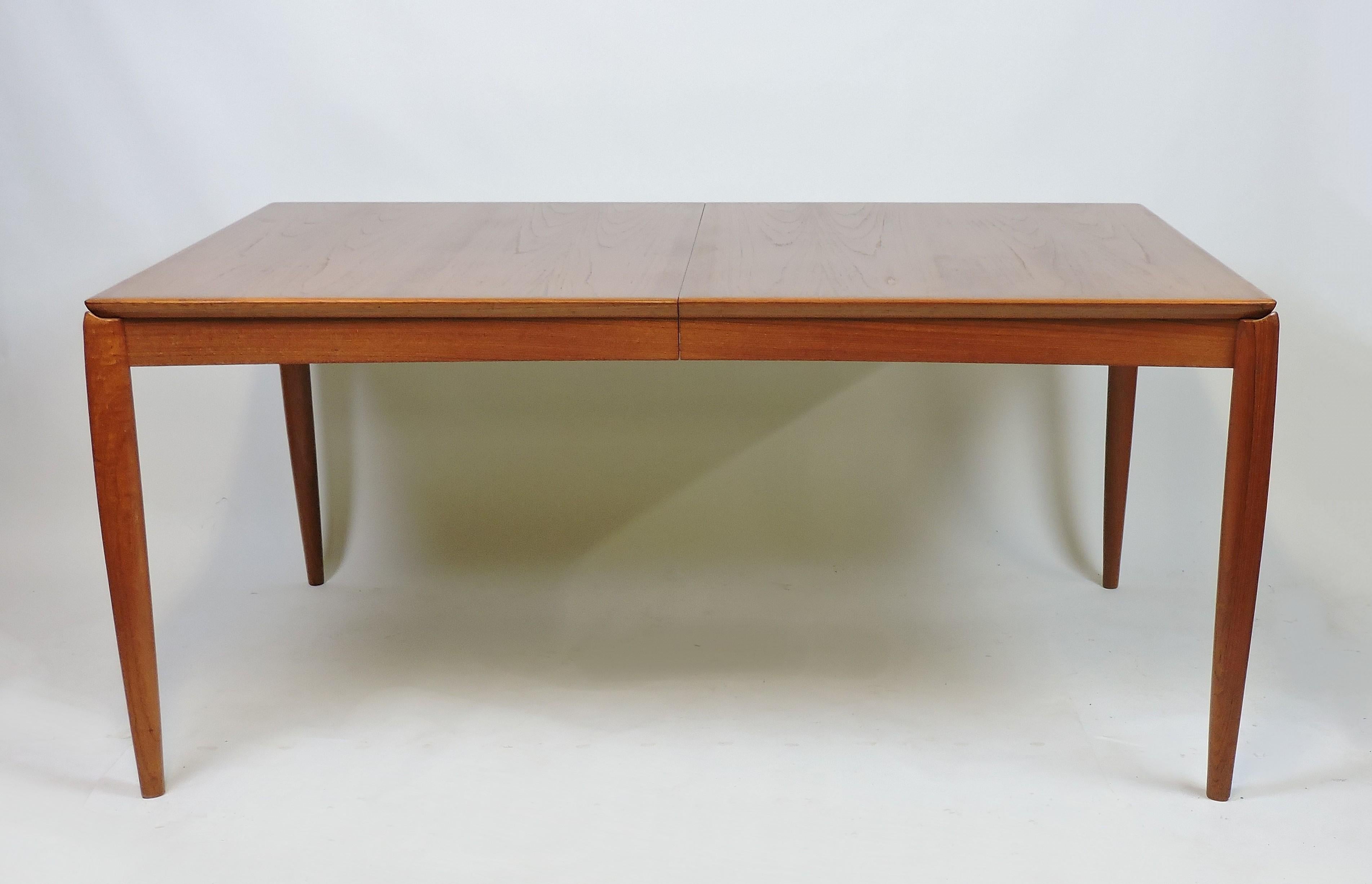 Elegant dining table designed by H.W. Klein and manufactured in Denmark by Bramin. This table has sculpted solid teak legs along with beautiful wood grain and color. A self-storing leaf allows it to extend from 63 1/4 inches to a nice size of 87