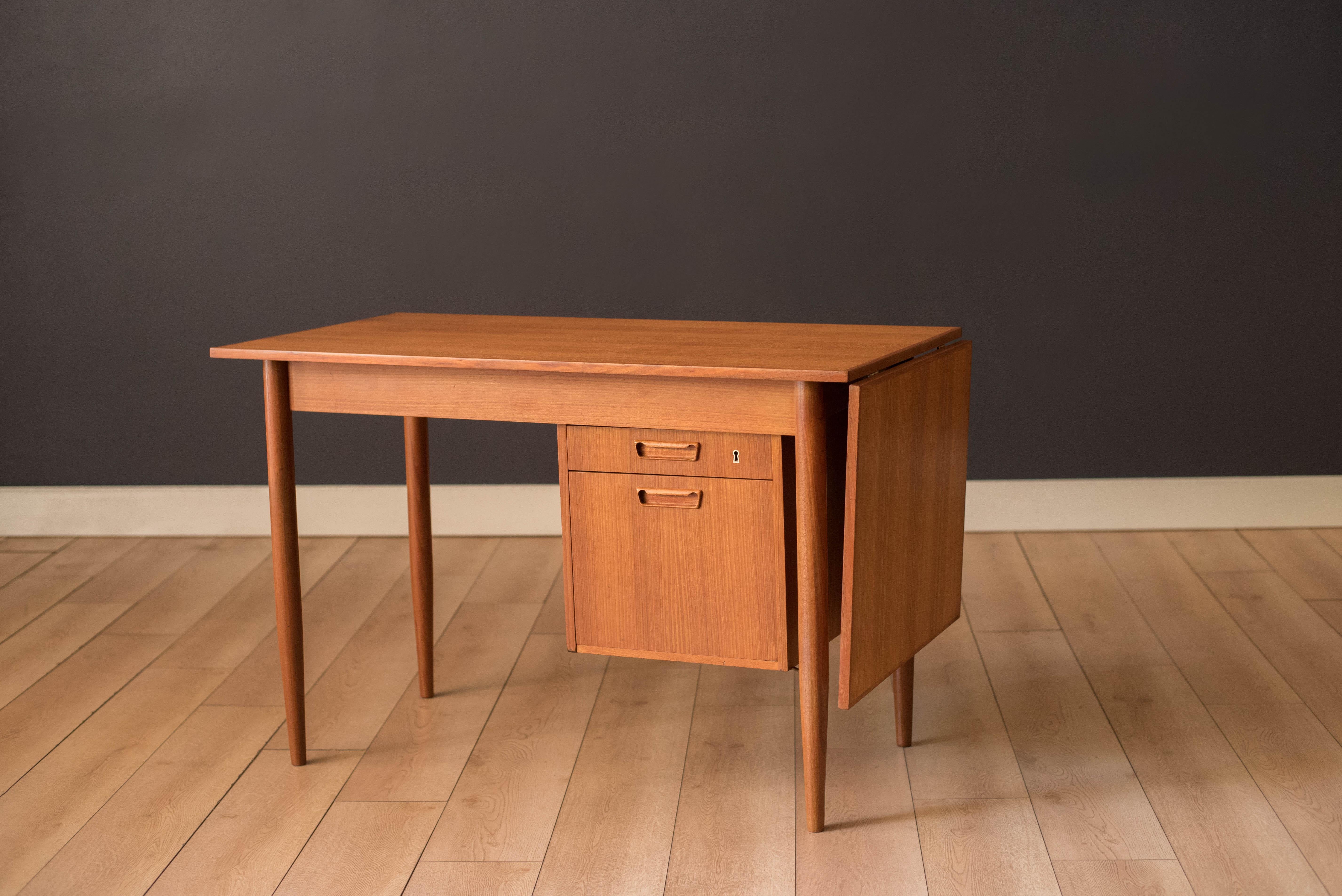 Mid-Century Modern expandable desk in teak designed by Gunnar Nielsen Tibergaard, Denmark. This versatile piece features brass hardware and includes one extension drop leaf that conveniently slides over to increase your work surface space. Equipped