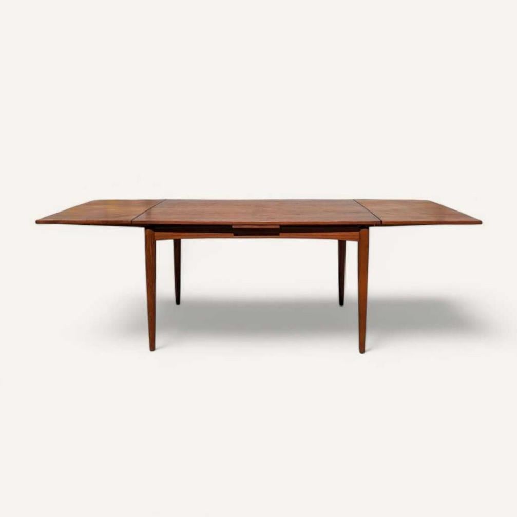 Una elegante y versátil mesa de comedor extensible de estilo moderno danés, fabricada en madera de teca y chapa de teca por el prestigioso fabricante danés Skovmand & Andersen. El diseño encarna la esencia del Modernismo escandinavo: líneas limpias,