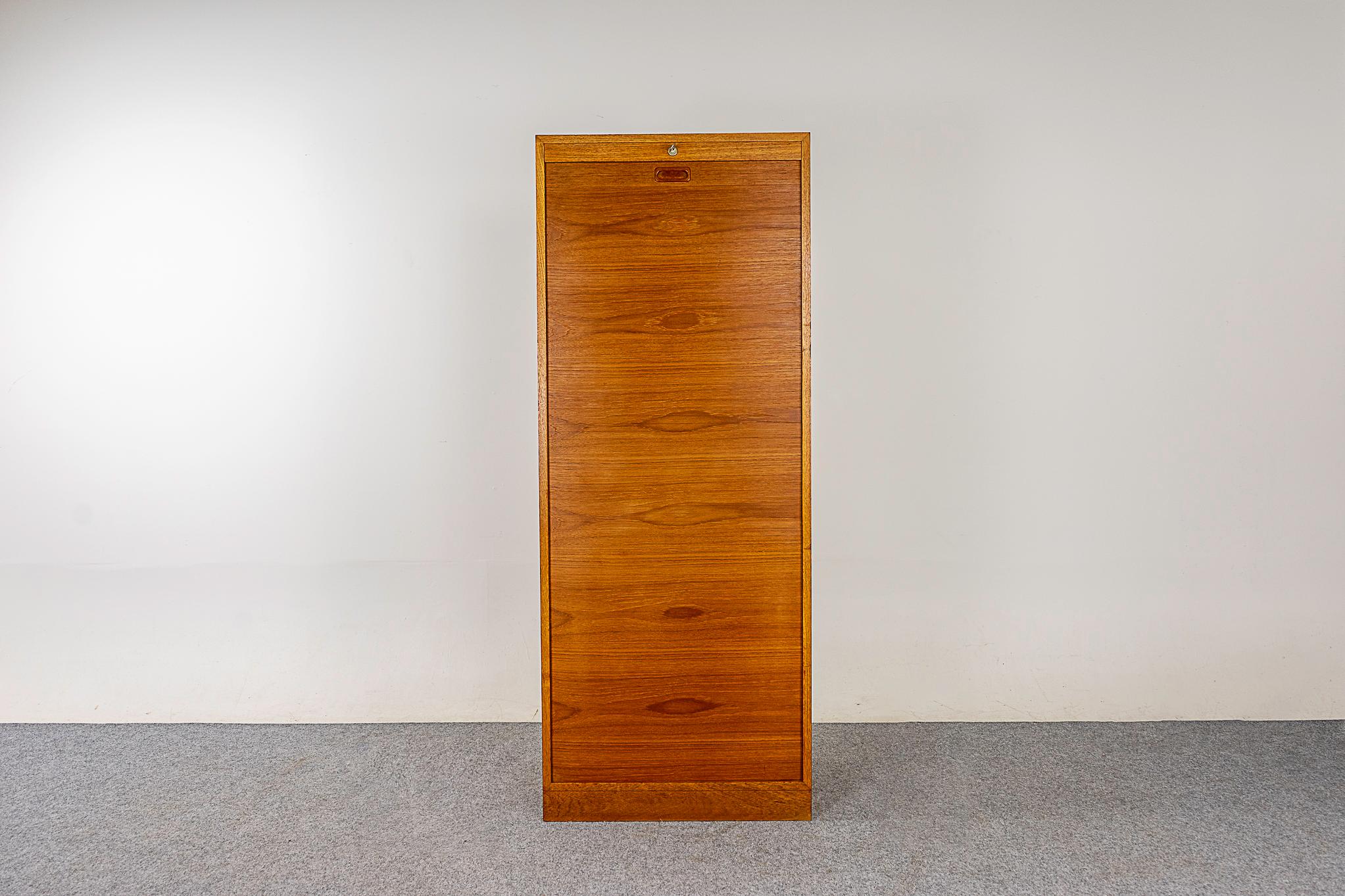 Teak Danish modern file cabinet, circa 1960's. Clean and modern. Magical tambour door neatly tucks inside itself. 2 adjustable shelves that can be hung at 20 options.